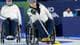 Tyler McFarland / Bildbyrån To personer sitter i rullestoler mens de deltar i en curlingaktivitet. Den ene personen holder en curlingsten og retter seg mot isen. Omgivelsene har en sportsarena som bakgrunn, med publikum synlig. Det er en konkurransesituasjon med fokus på rullestolcurling. (Bildebeskrivelsen er laget av en KI-tjeneste)
