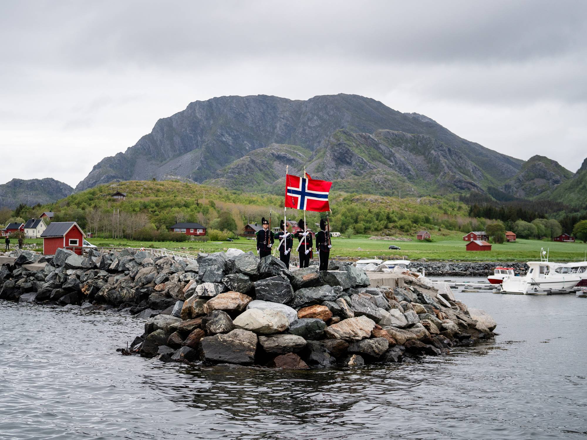Gardister står med et norsk flagg ute på en molo under kongen og dronningens fylkesreise i Nordland i 2023