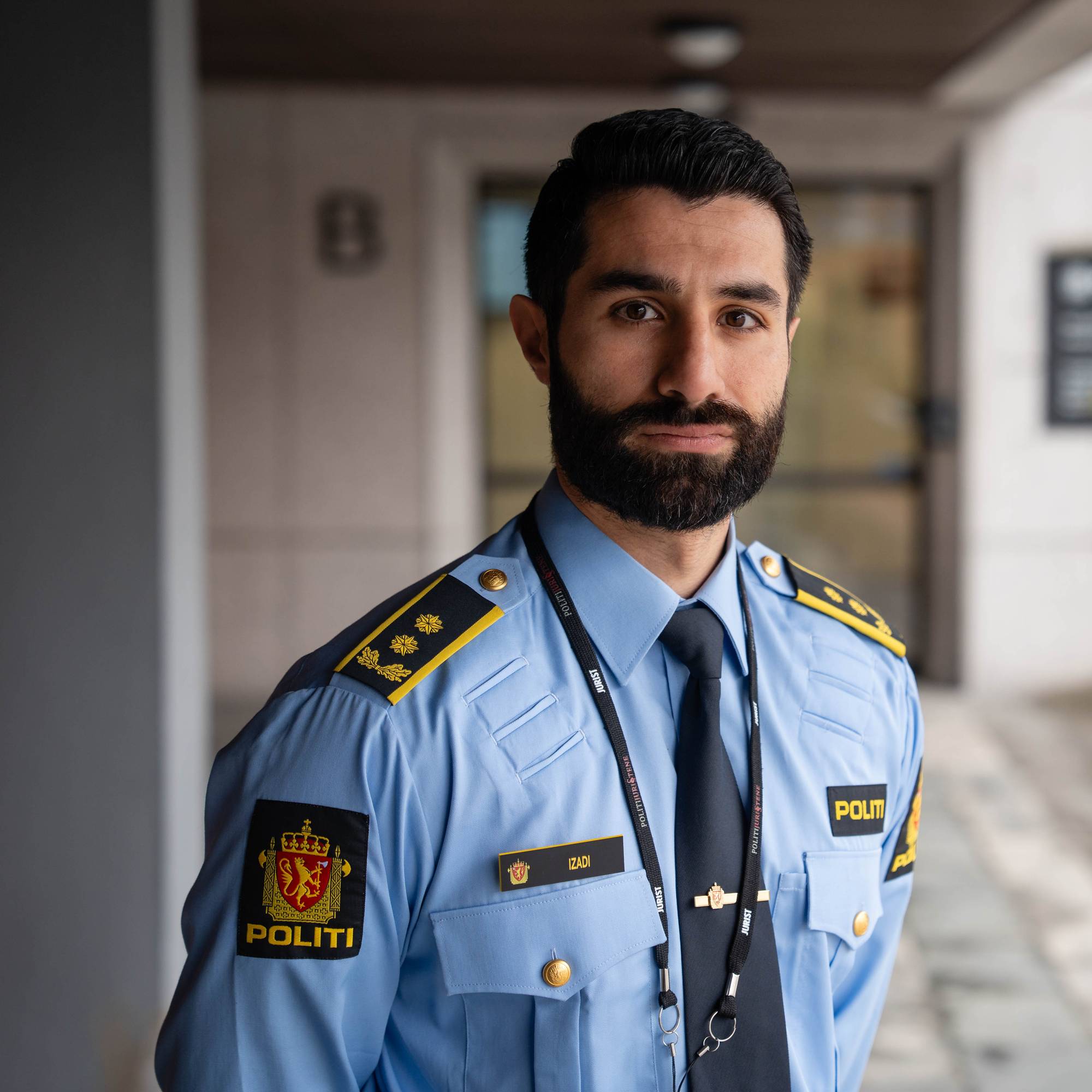 mann med svart hår og skjegg i politiuniform