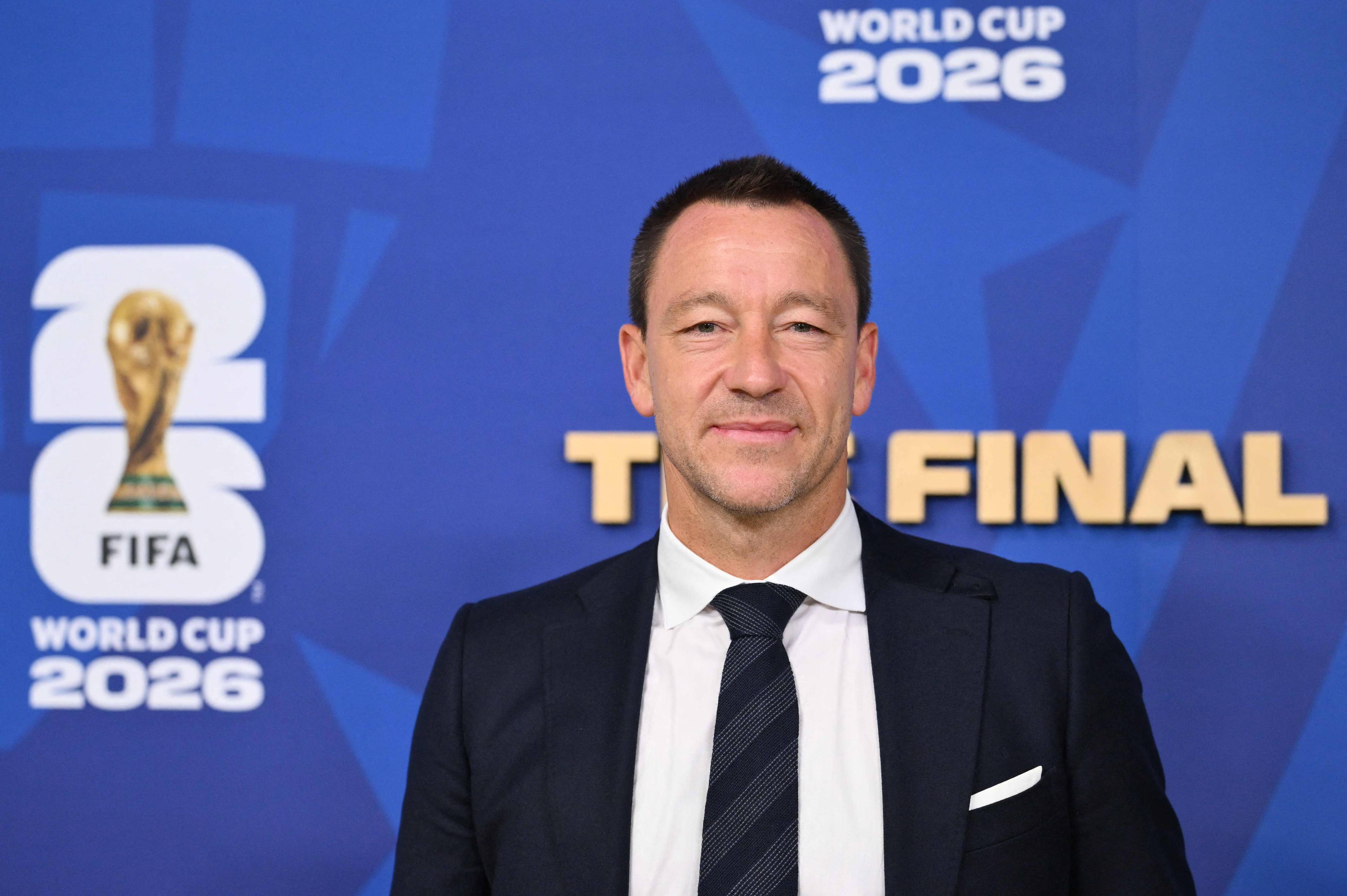 John Terry foran en bakgrunn med logo for VM i fotball 2026. (Bildebeskrivelsen er laget av en KI-tjeneste)