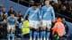 Foto: Jason Cairnduff / Reuters / NTB Spillere fra Manchester City feirer etter et mål. Laget har på seg lysere blå drakter med sponsorlogo. En tilskuer i oransje vest står i bakgrunnen. Stemningen er hektisk med publikum i antrekk tilpasset arrangementet.