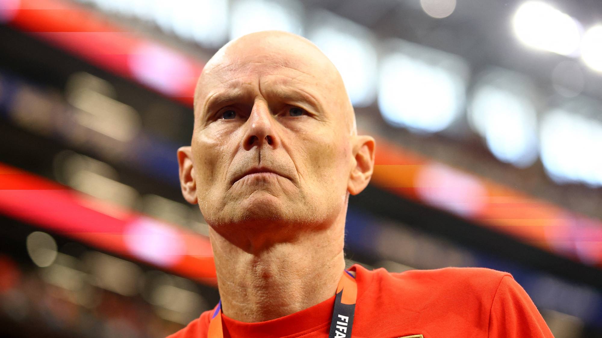 Ståle Solbakken med alvorlig ansiktsuttrykk i rødt landslagstøy på en fotballstadion. (Bildebeskrivelsen er laget av en KI-tjeneste)