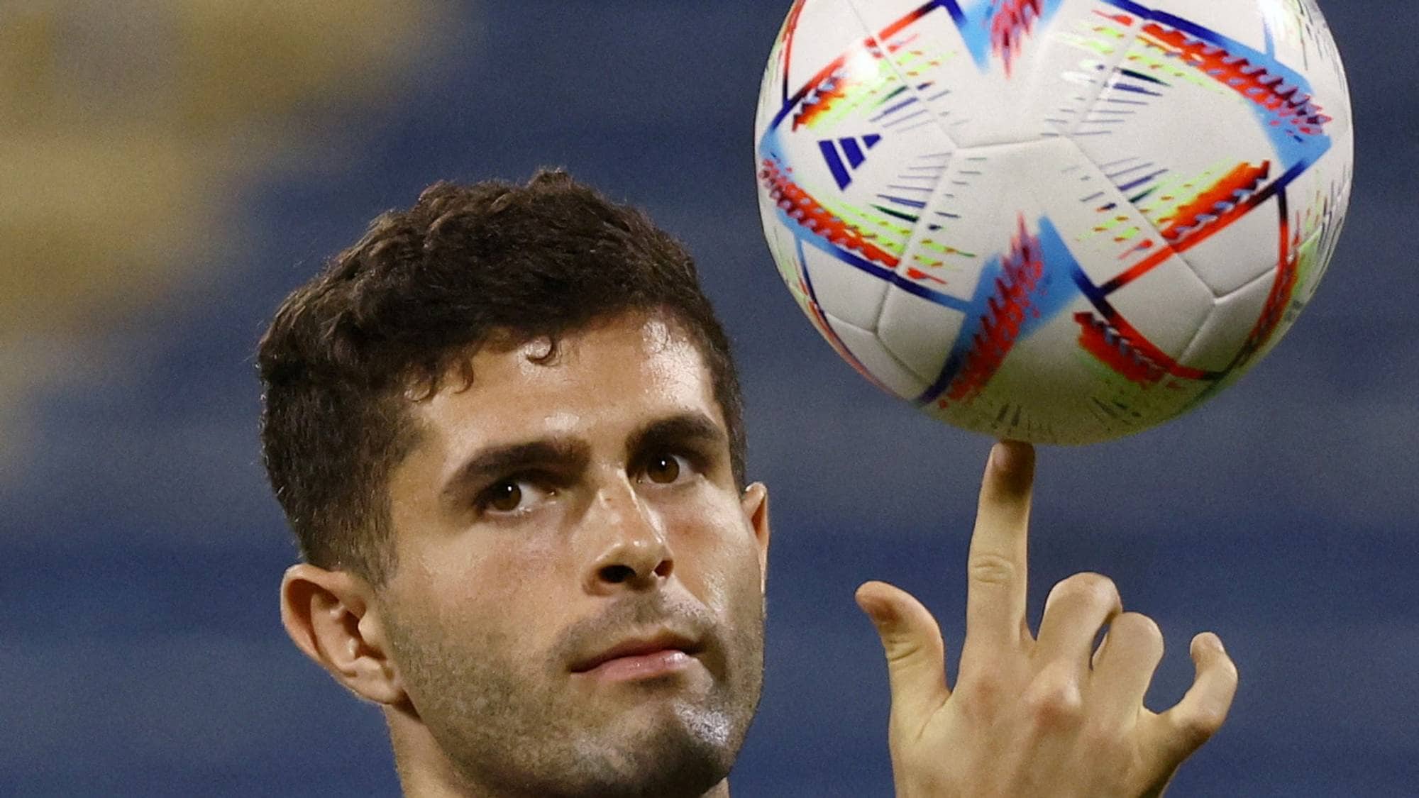 Christian Pulisic spinner en fotball på fingeren. Han har på seg en blå drakt med et hvitt Nike-merke. Bakgrunnen er utydelig. (Bildebeskrivelsen er laget av en KI-tjeneste)