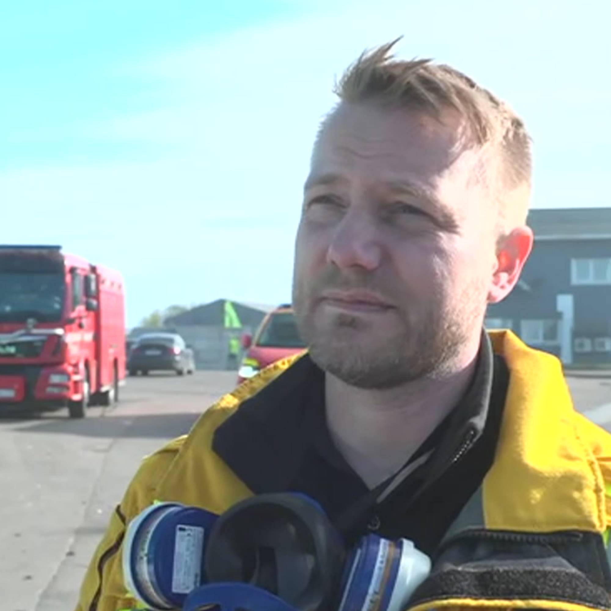 Trond Atle Haglind har på brannuniform. I bakgrunnen er det flere bygg og en brannbil.