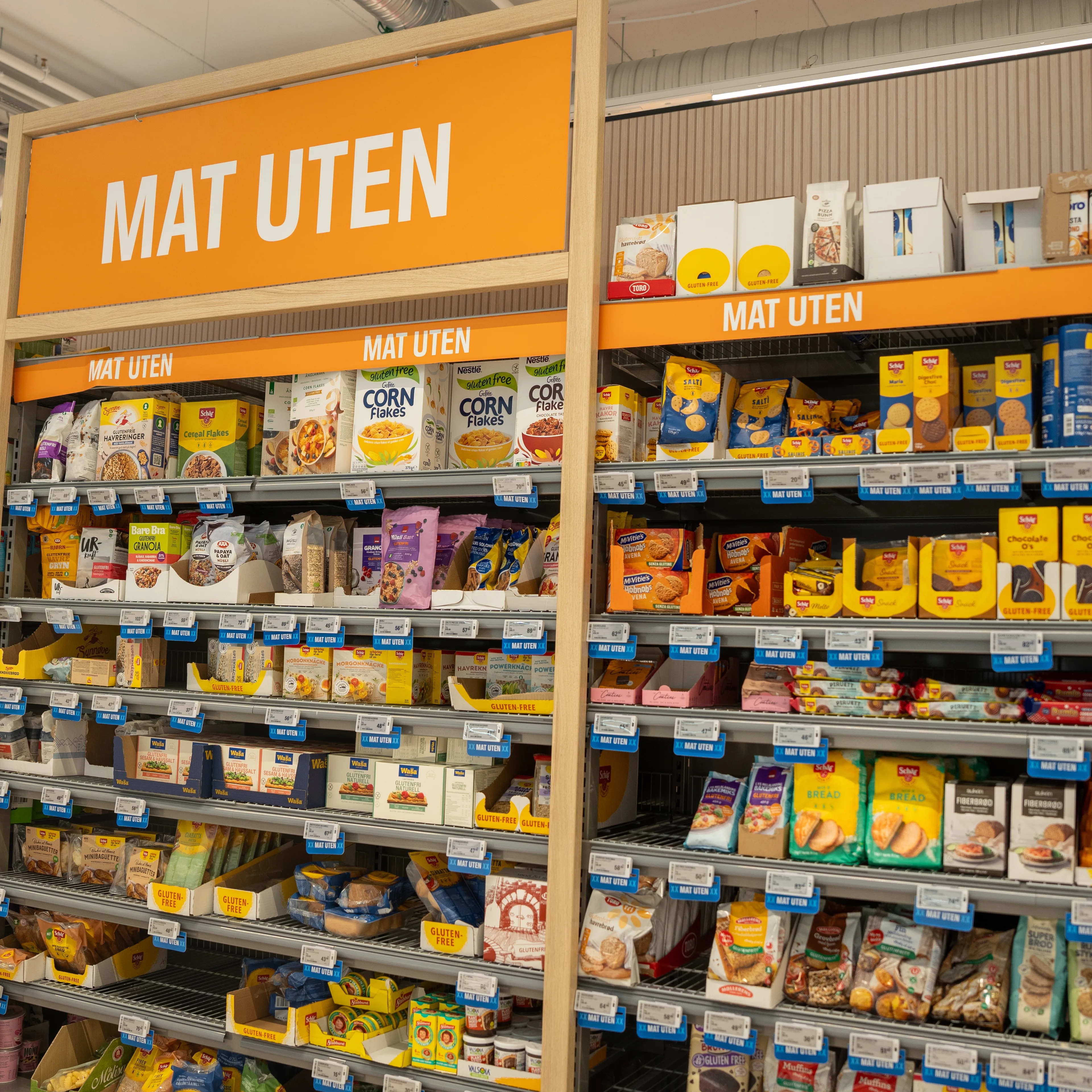 Butikkhyller med et stort utvalg av glutenfrie matvarer merket med skilt. (Bildebeskrivelsen er laget av en KI-tjeneste)