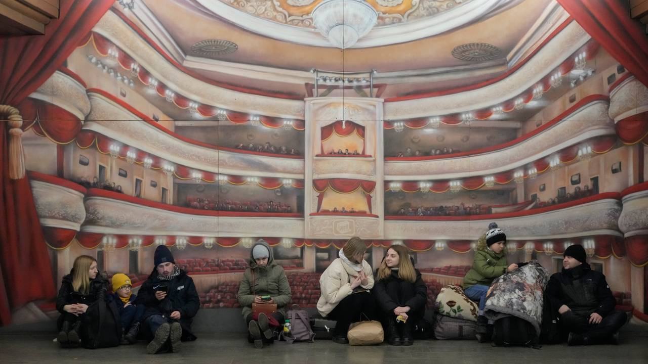 Folk hviler inntil veggen på t-banestasjonen i Kyiv.