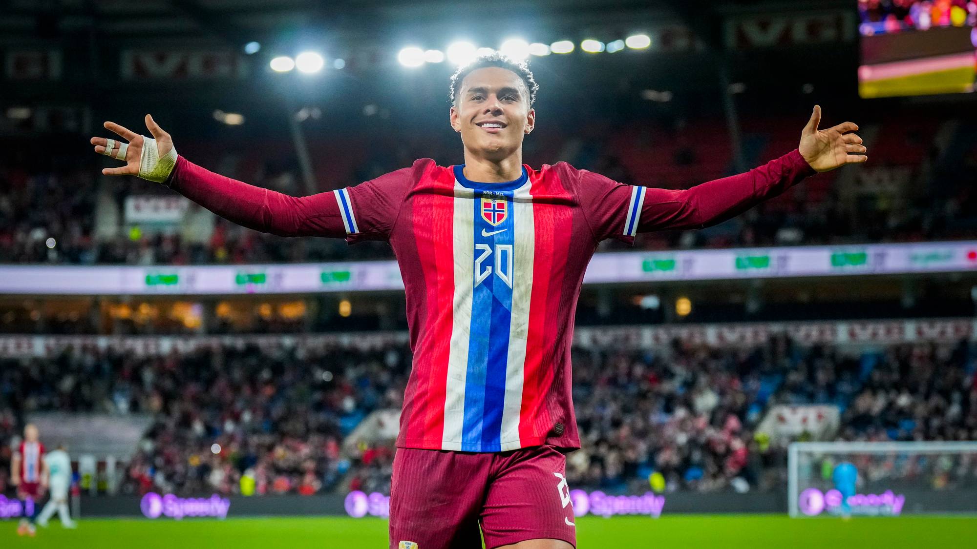 en mann i sportsuniform med armene hevet på et stadion