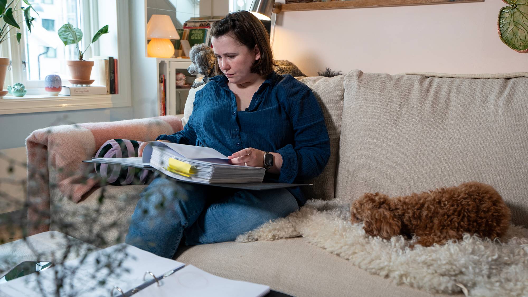 en person som sitter på en sofa og leser en bok