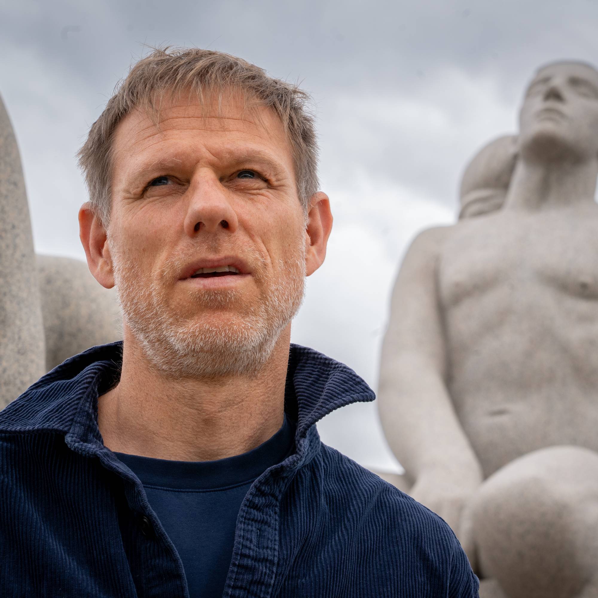 Mann kikker ut i lufta med blå jakke