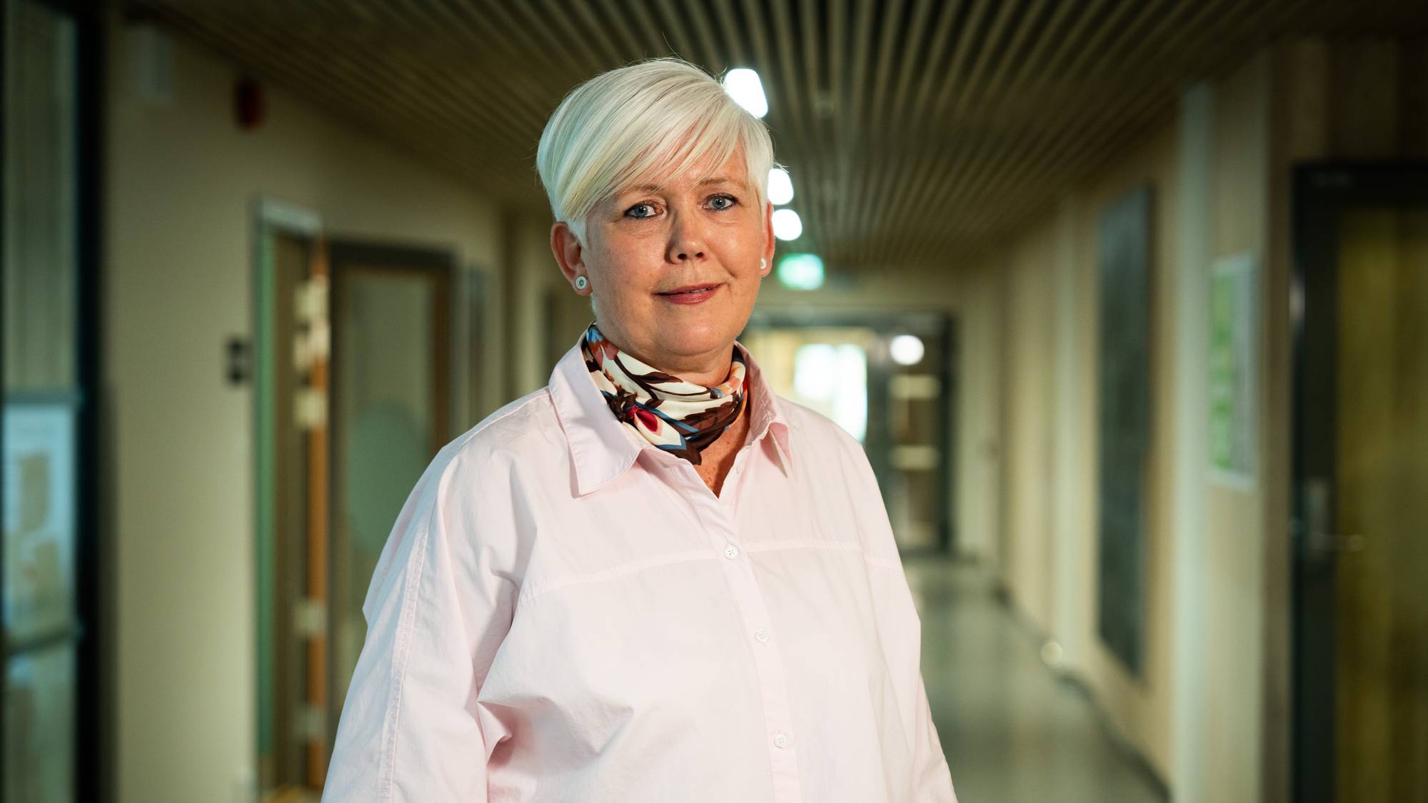 Kvinne med lyst hår står i korridoren på skolen. 