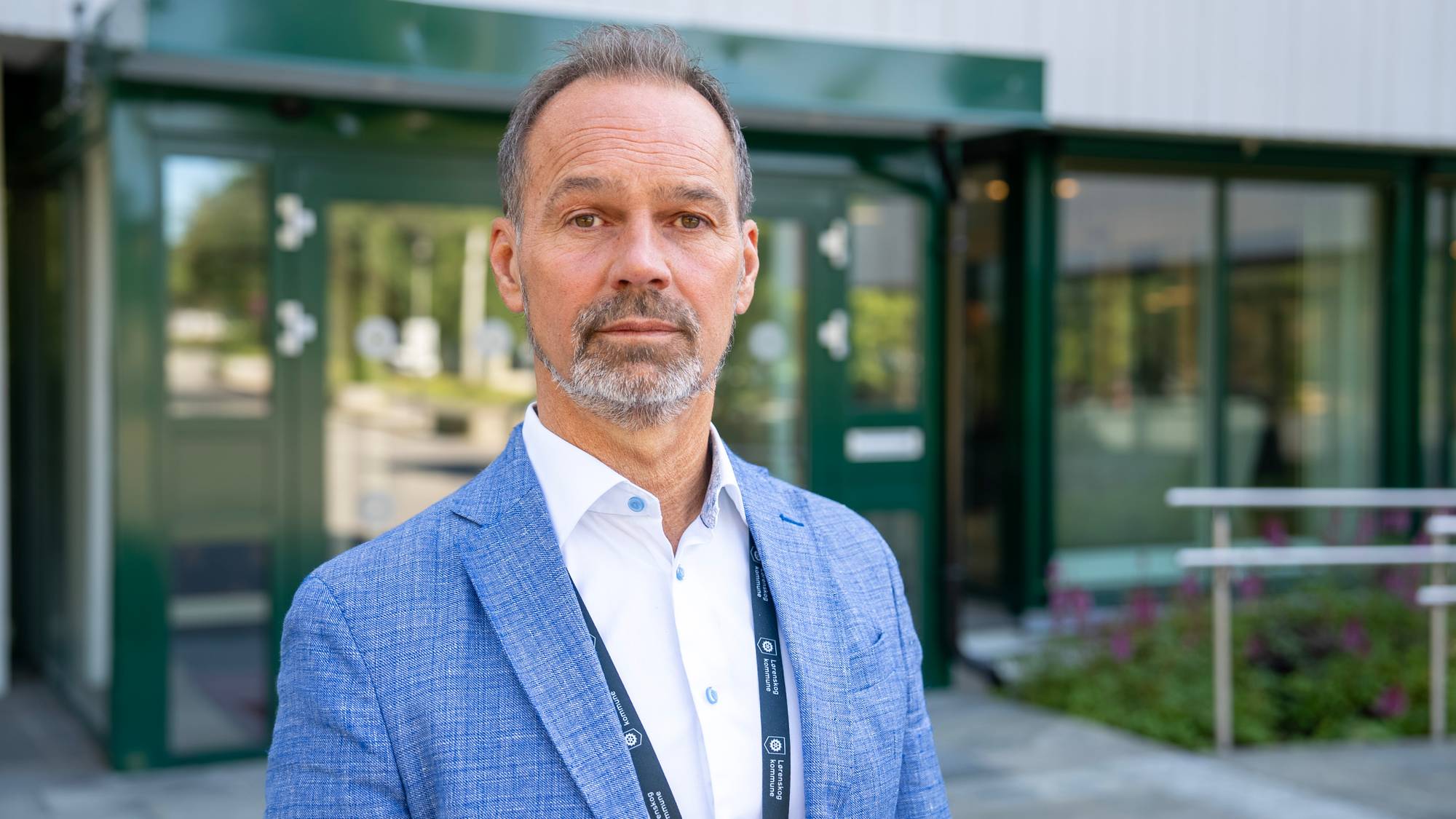 Mann med lysblå blazer og skjegg ser inn i kamera