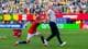 Fredrik Varfjell / NTB Fotballspiller i norsk landslagsdrakt holder en mann i hvit t-skjorte på en fotballbane. (Bildebeskrivelsen er laget av en KI-tjeneste)