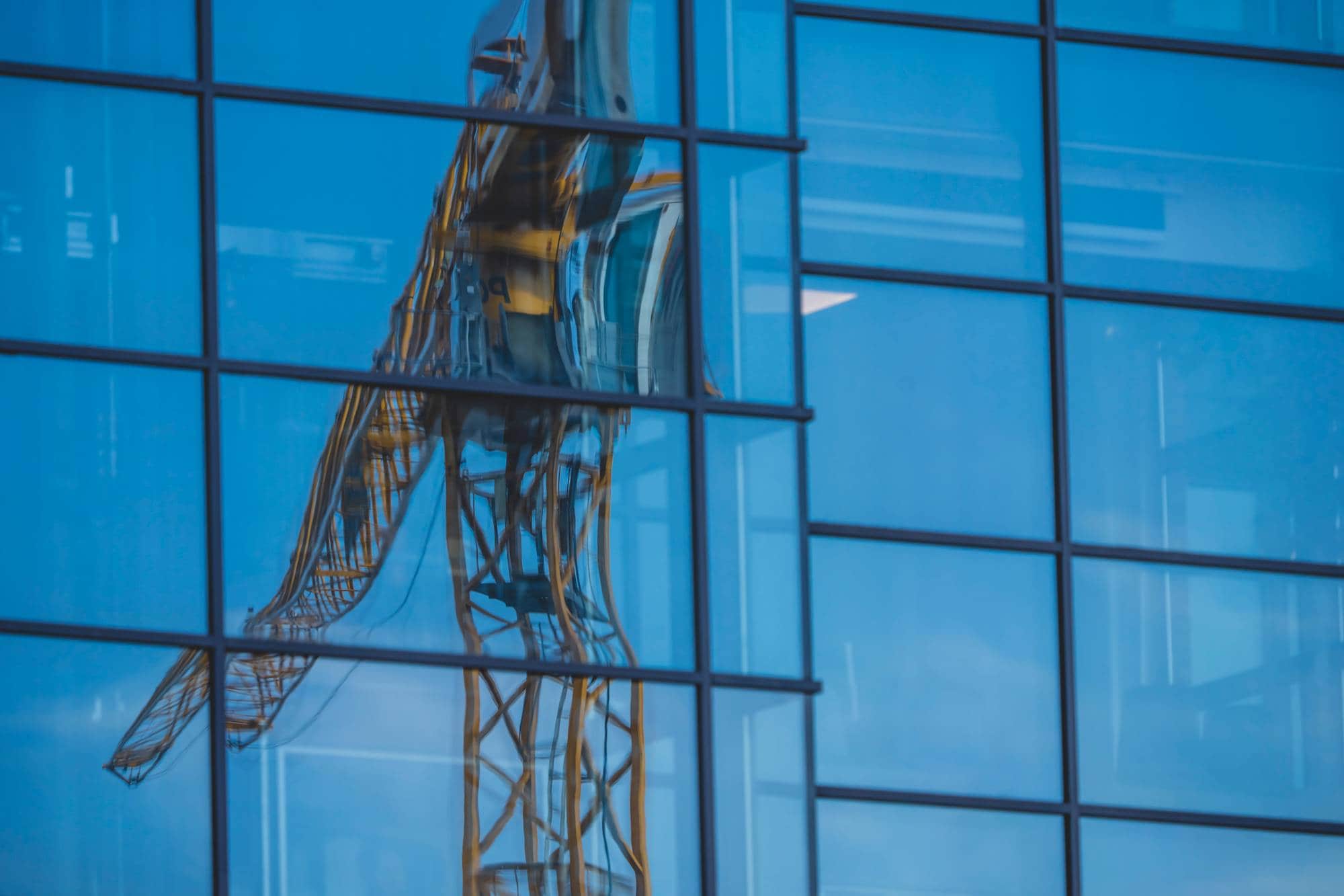 Bildet viser anleggsaktivitet med tårnkraner, gravemaskiner og betongarbeid på et omfattende område som tidligere var industri, men som nå transformeres til et boligområde. 