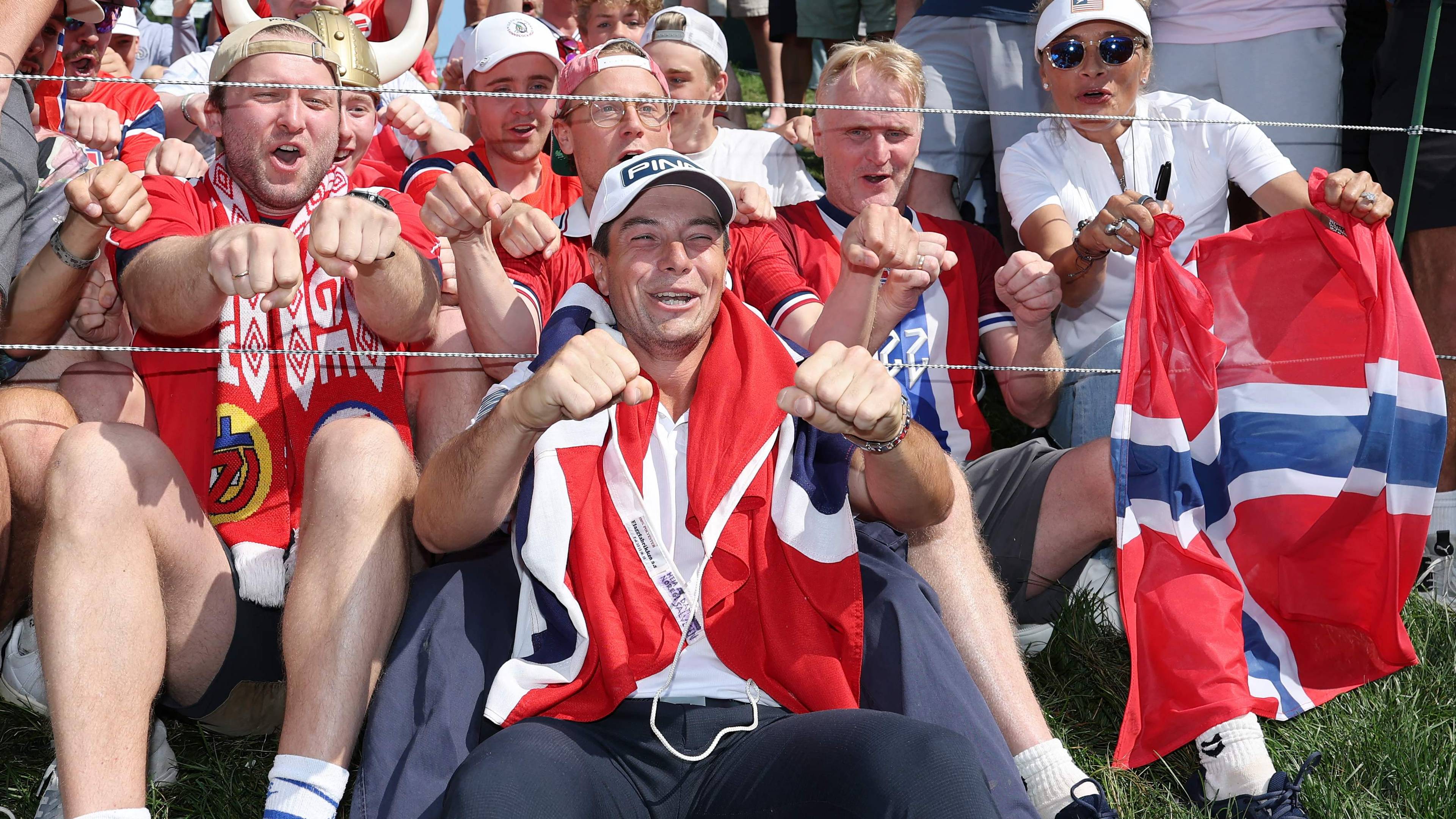 Golfspiller Viktor Hovland feirer med jublende supportere som holder norske flagg. (Bildebeskrivelsen er laget av en KI-tjeneste)