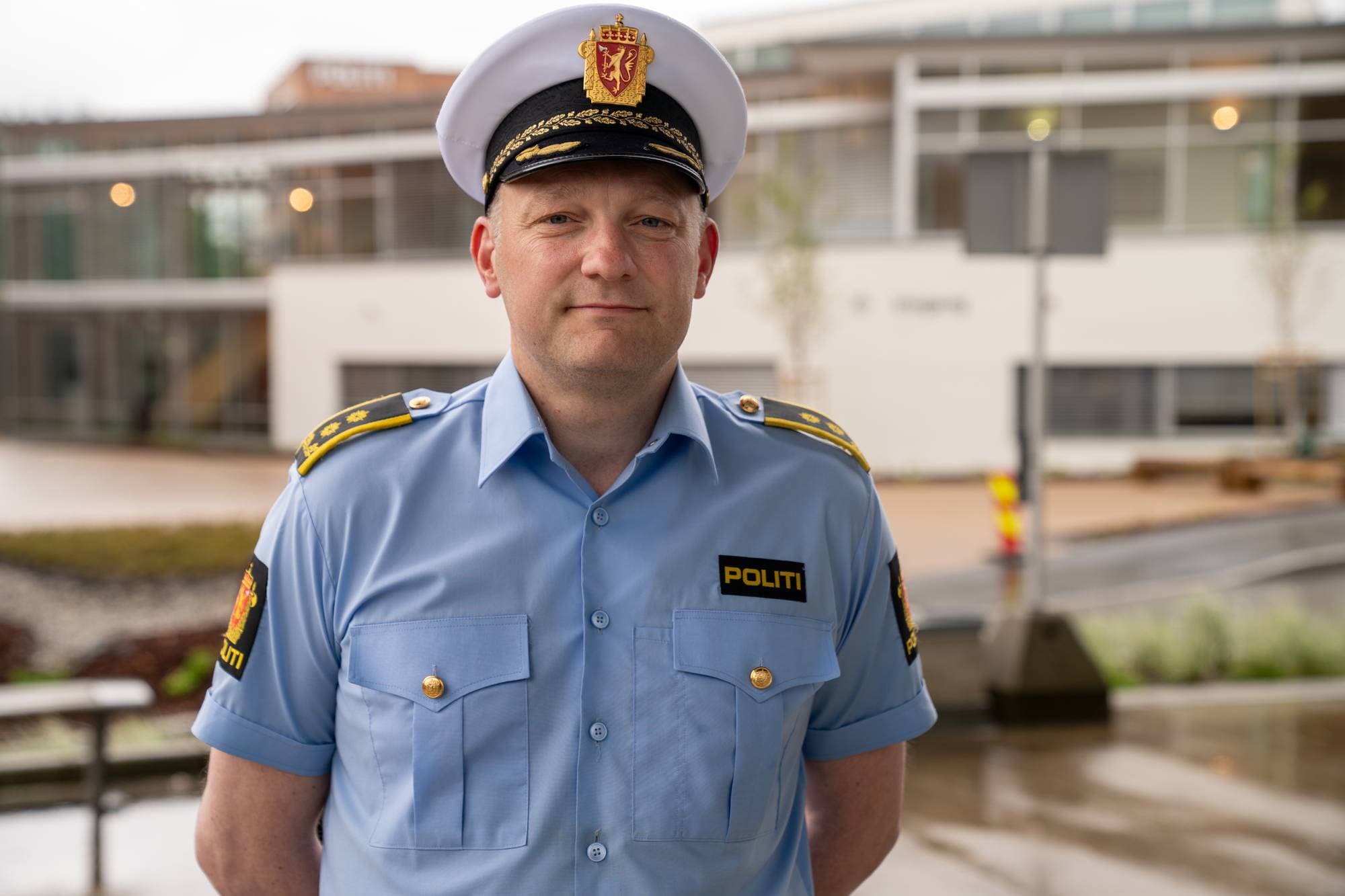 Politimann med hatt utendørs. 