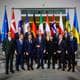 MARKUS SCHREIBER / AFP / NTB Bildet viser en gruppe politikere samlet for et offisielt fotografi. De står på en trapp foran flere nasjonale flagg, inkludert flaggene til NATO, EU og flere europeiske land. Deltakerne er iført forretningsklær og ser mot kameraet. Omgivelsene er moderne, med en lys interiørstil og kunstverk i bakgrunnen. (Bildebeskrivelsen er laget av en KI-tjeneste)