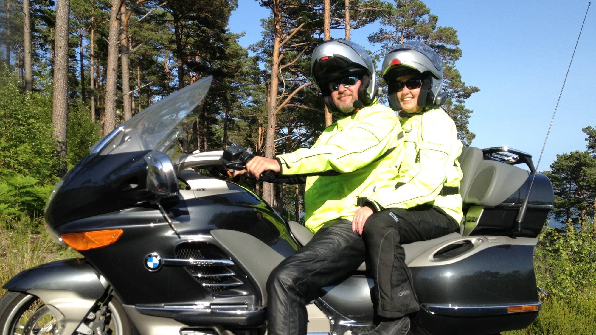 ein mann og ei kvinne med svarte bukser og gule jakker på ein motorsykkel 