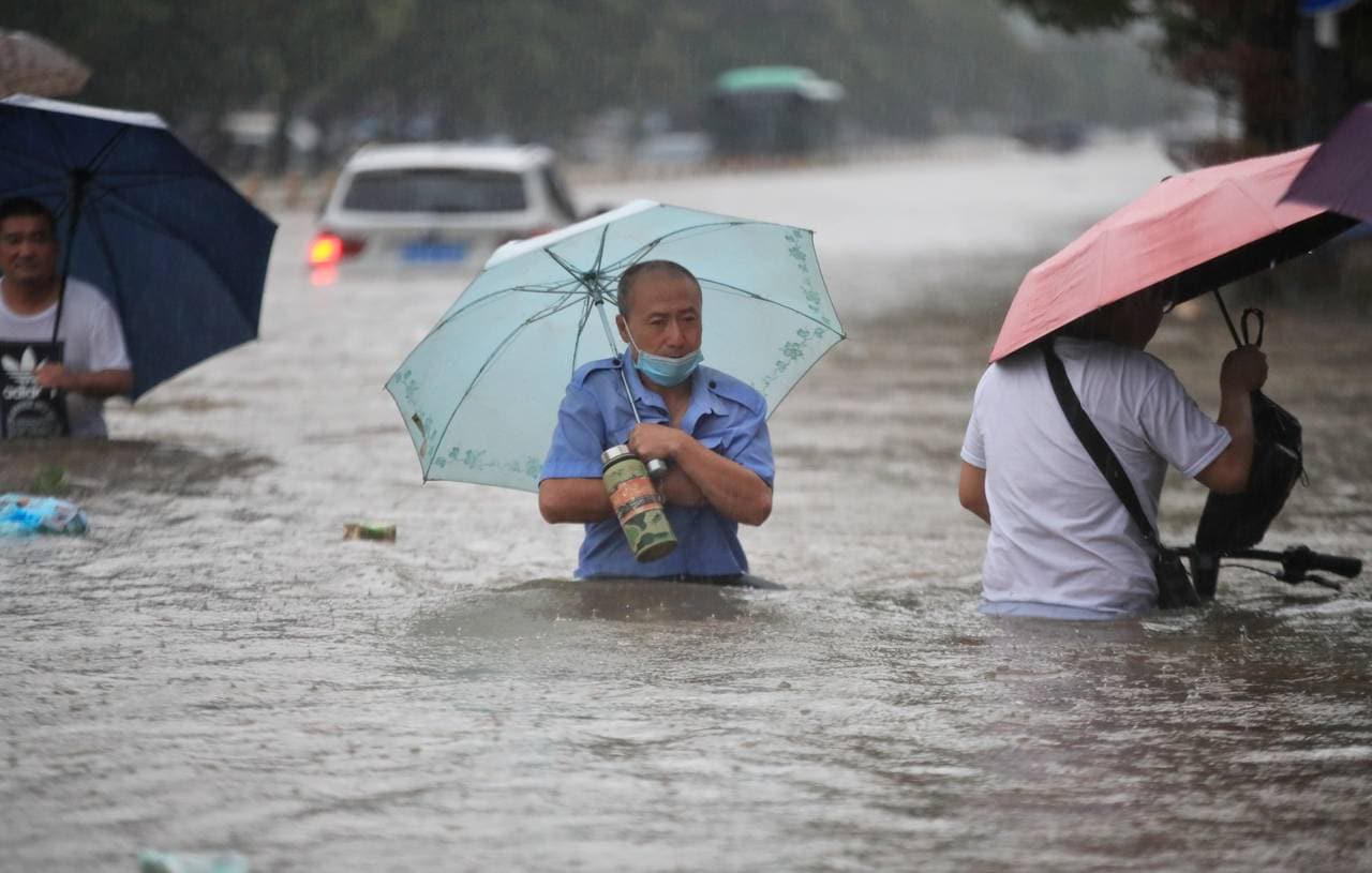 En mann vasser gjennom flomvann etter kraftig nedbør i byen Zhengzhou. 