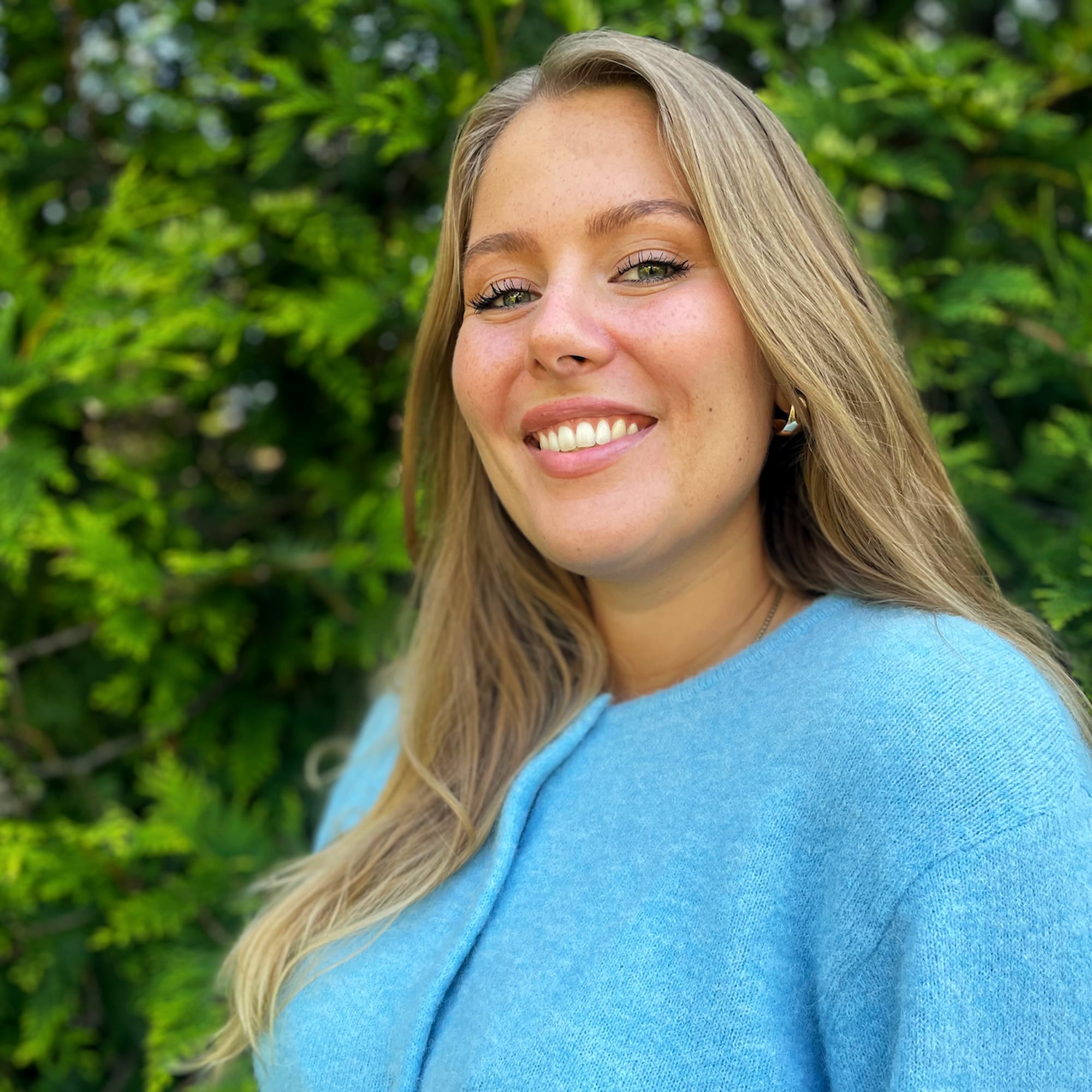 Kvinne med langt lyst hår og blå jakke 