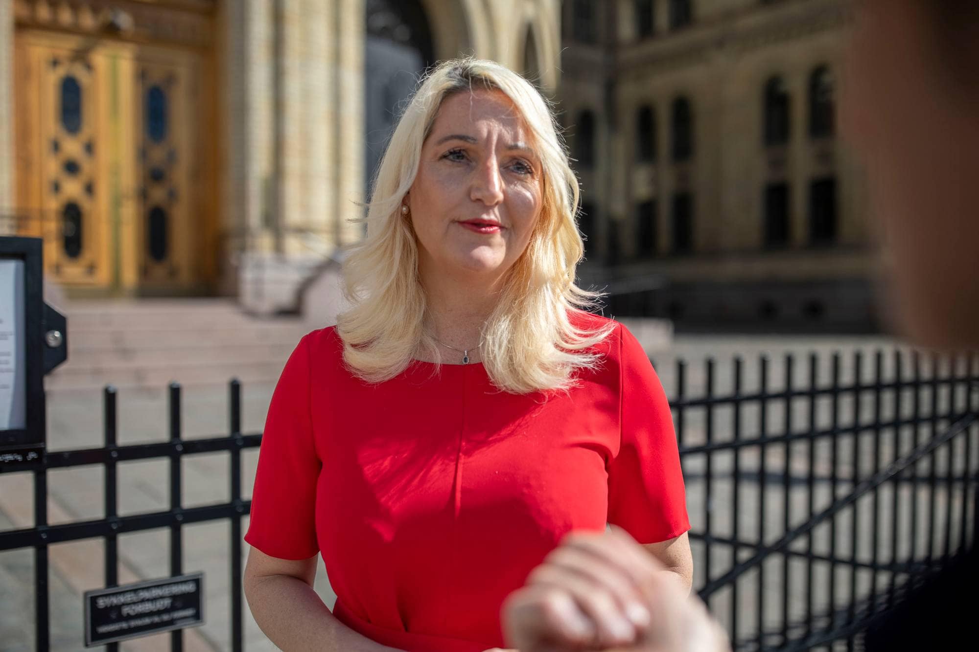 En kvinne med blondt hår. Hun står utenfor Stortinget. 