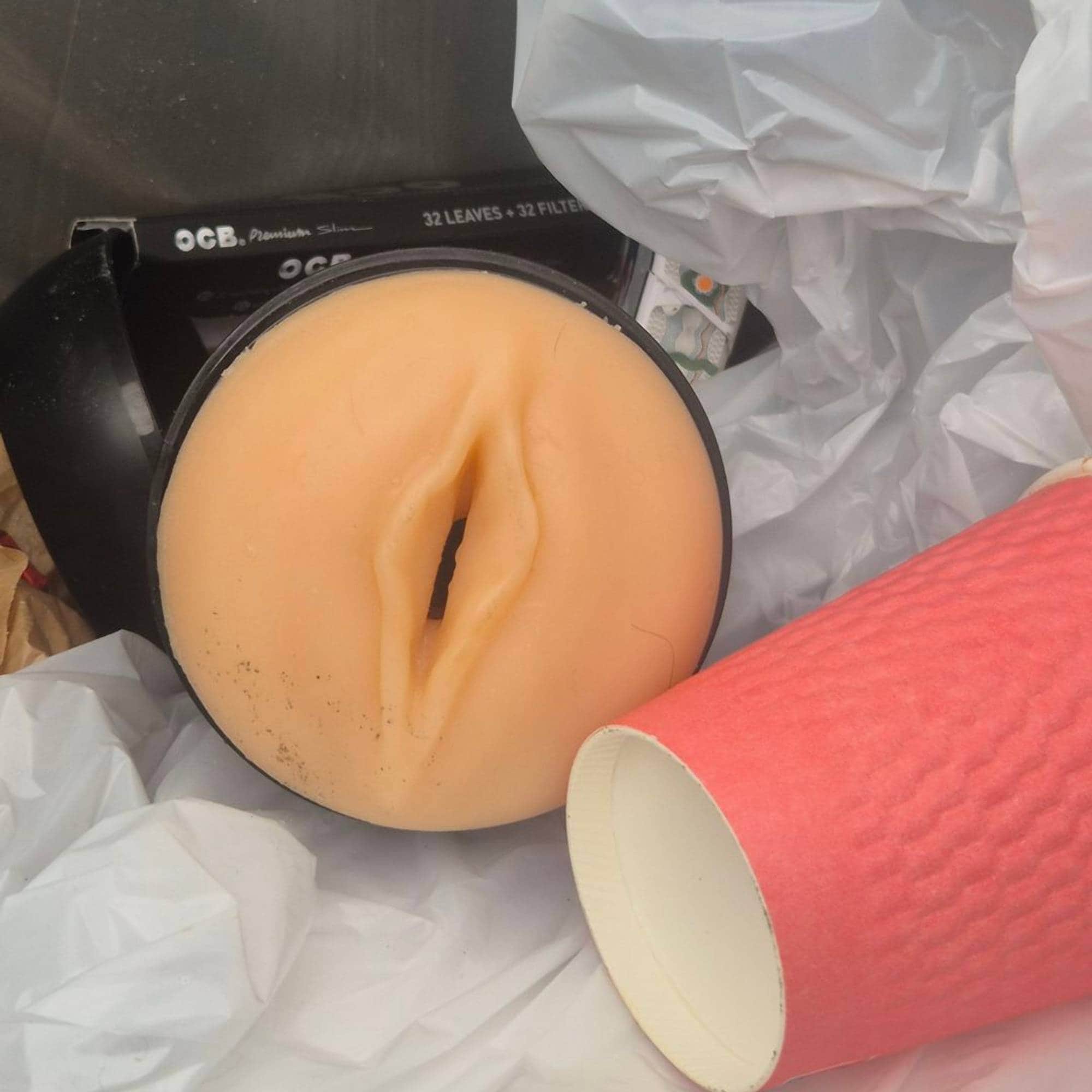 Et seksuelt hjelpemiddel ligger i en pose sammen med en kaffekopp og en sigarettpakke. (Bildebeskrivelsen er laget av en KI-tjeneste)
