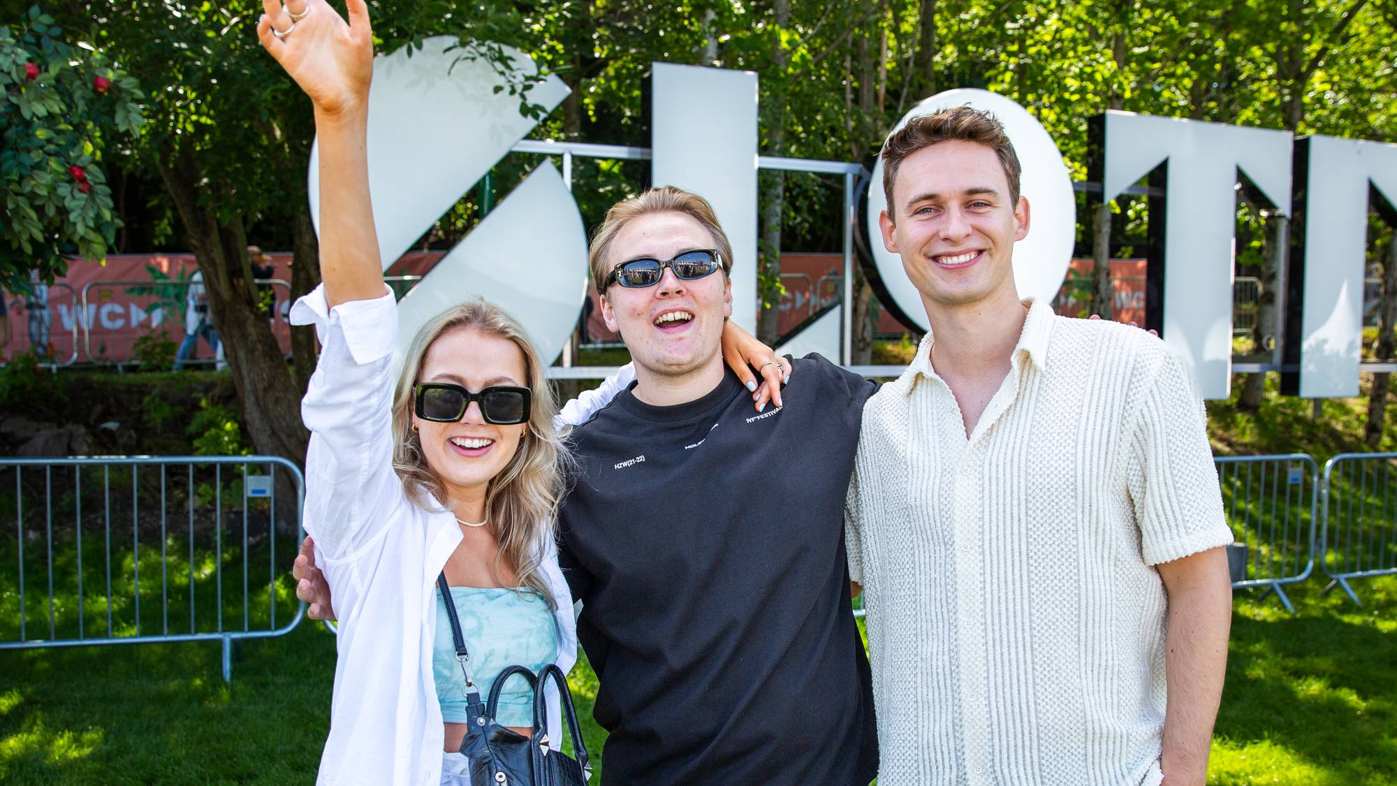 En jente og to gutter står foran skiltet «Slottsfjell» på festivalen i Tønsberg. De smiler og er glader.