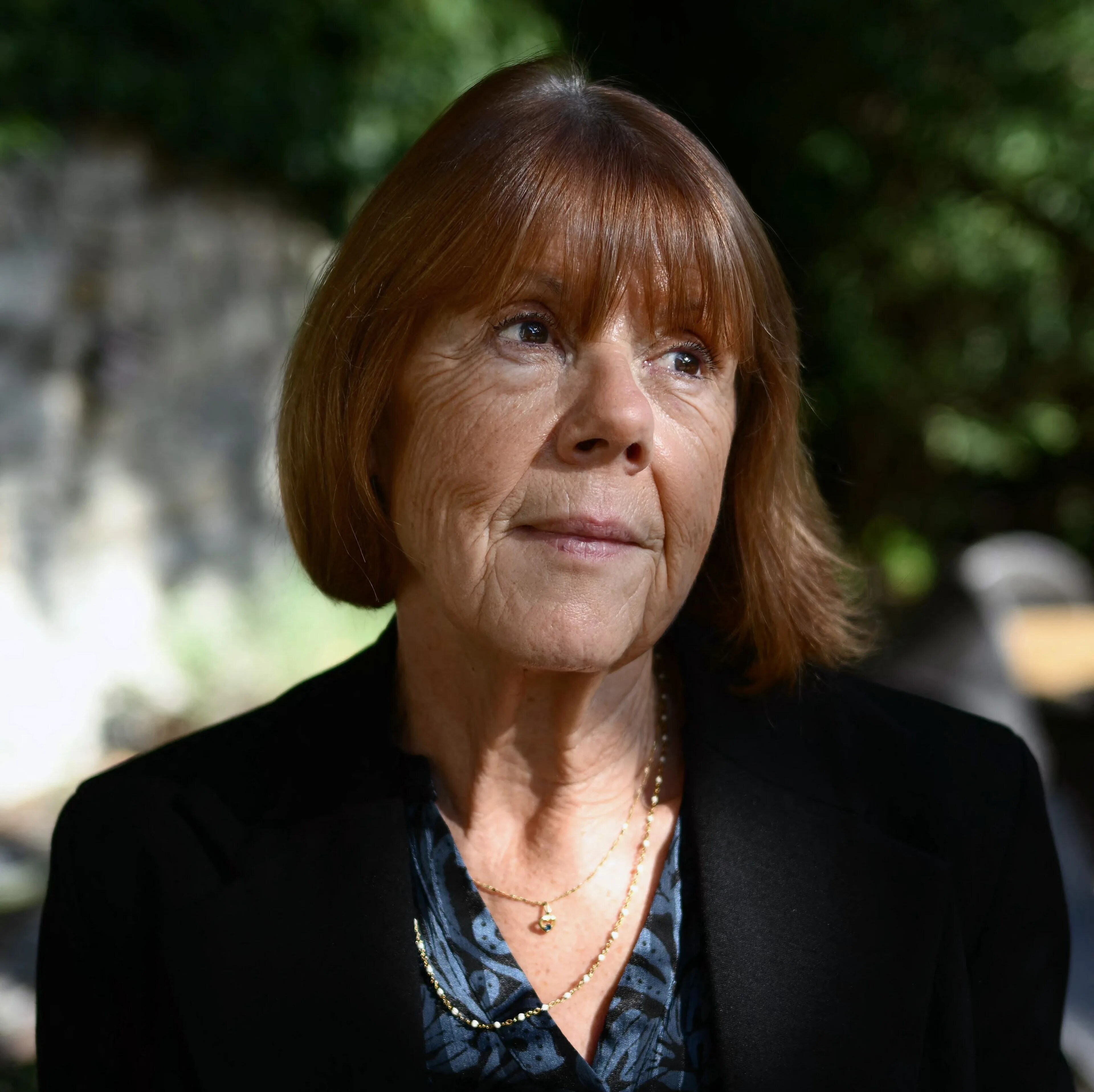 Portrett av en eldre kvinne med brunt hår i svart blazer og mønstret skjorte. (Bildebeskrivelsen er laget av en KI-tjeneste)