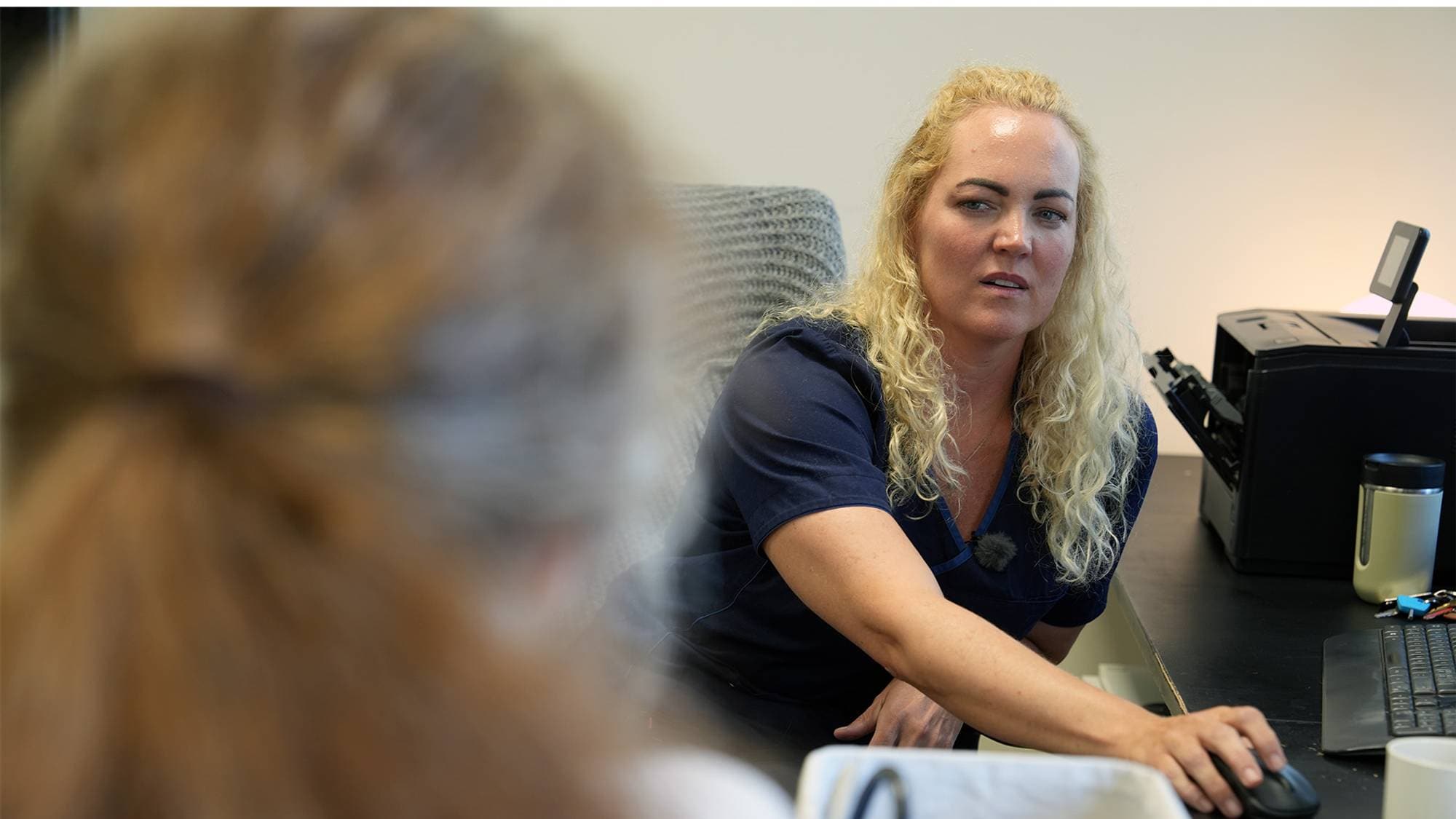 En person som sitter ved et skrivebord (Bildebeskrivelsen er laget av en KI-tjeneste)