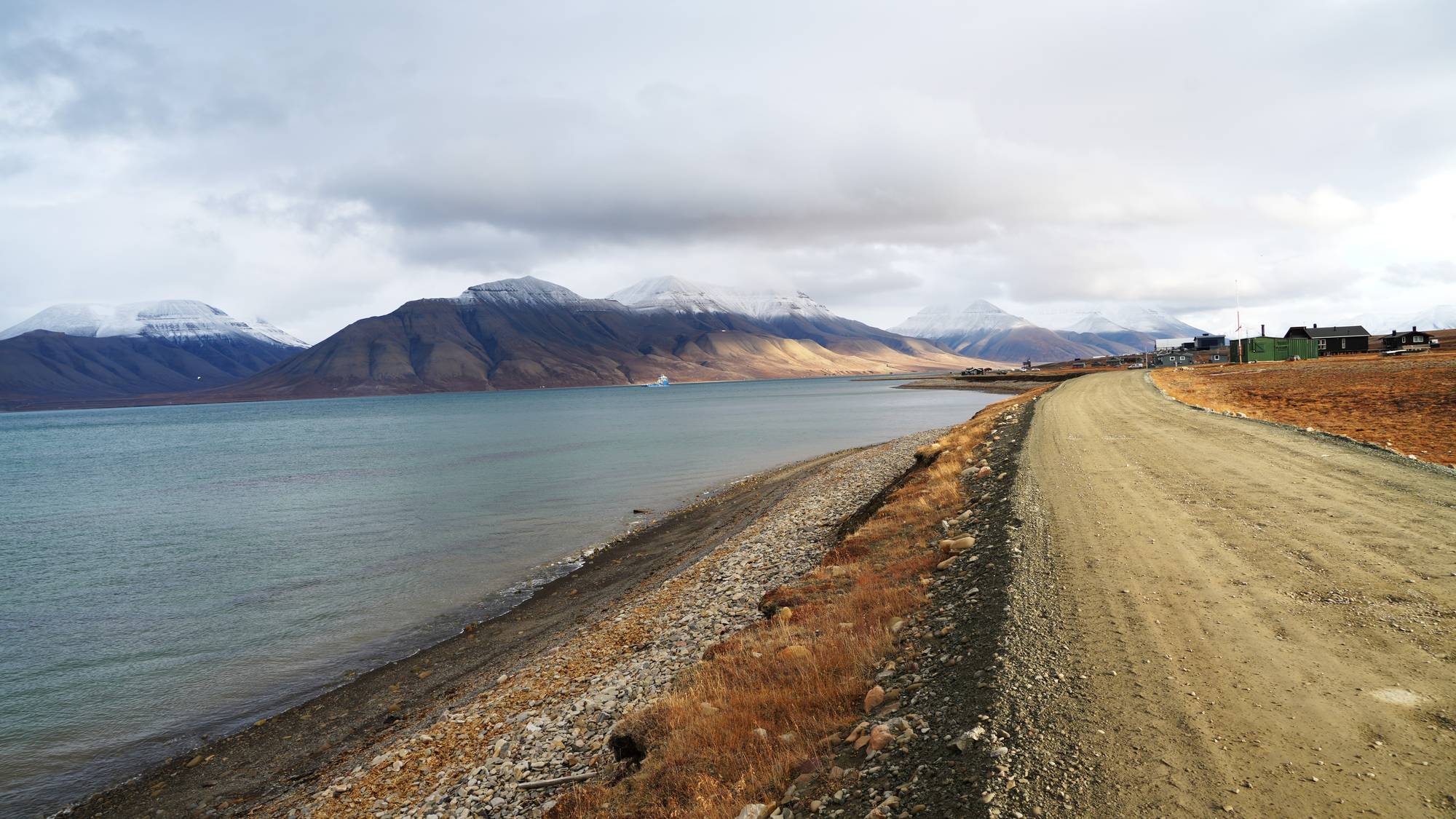 En vei langs havet med fjell i bakgrunnen. 