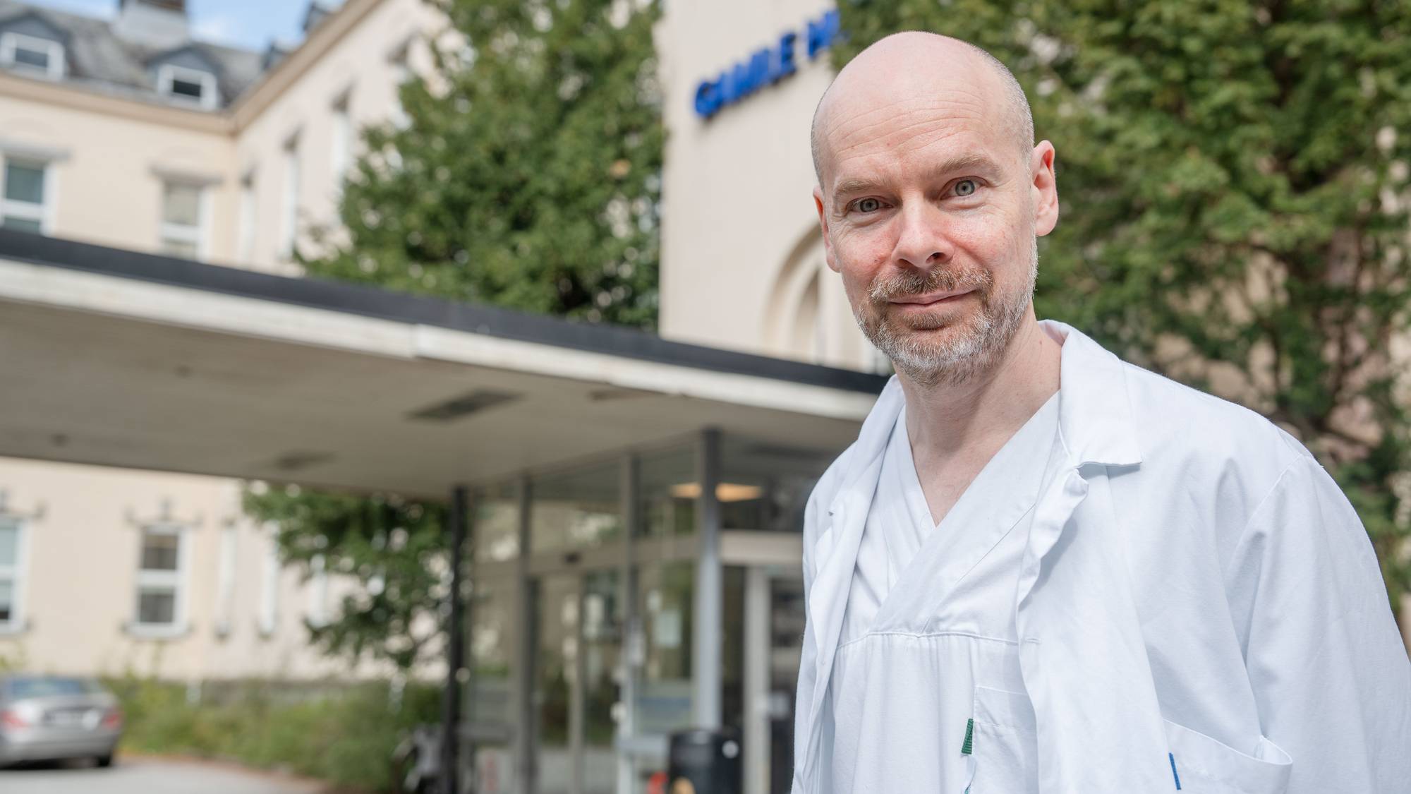 Forsker i legefrakk utenfor sykehusbygg