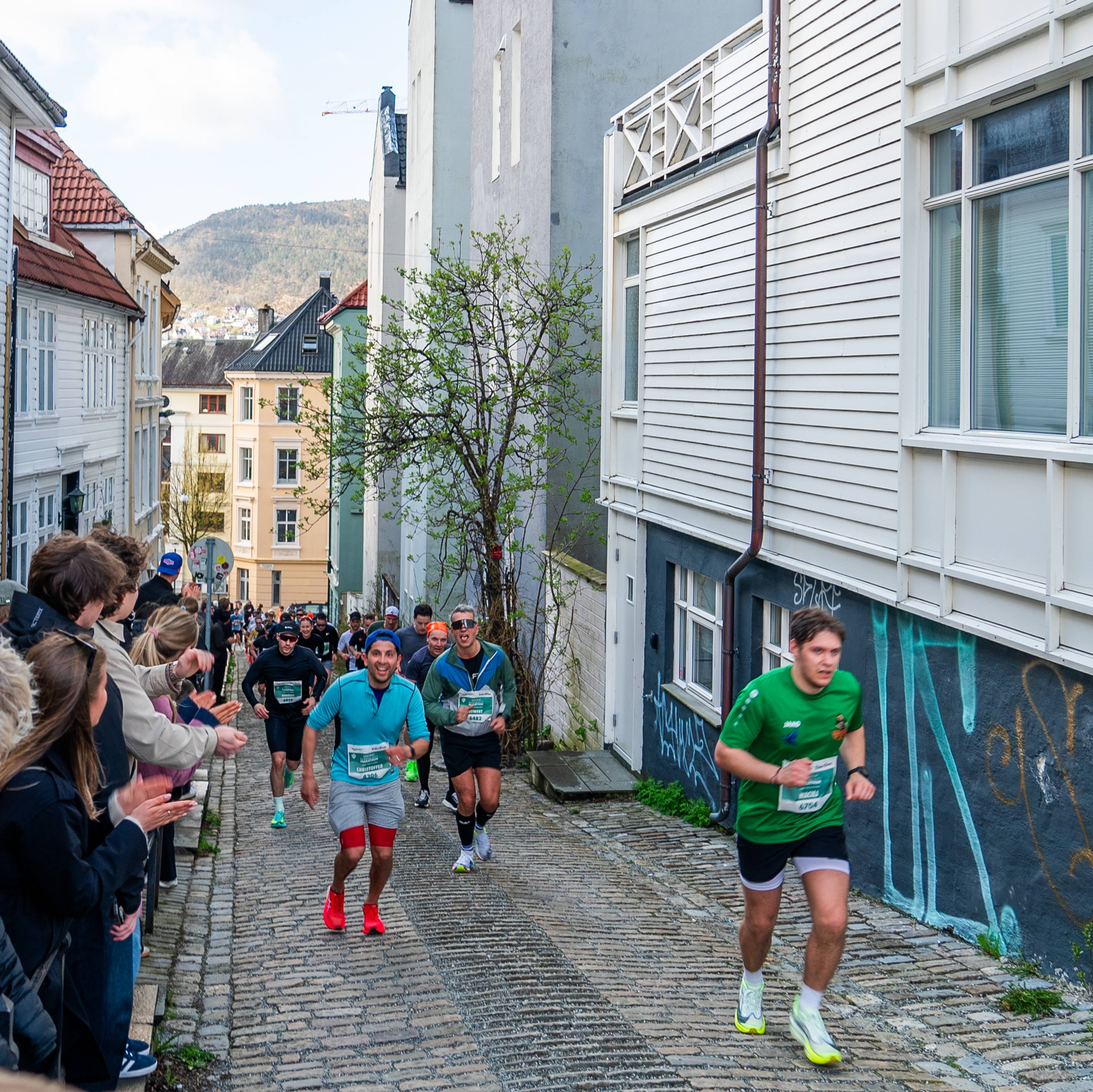 Bergen City Marathon 2026: løperar på veg gjennom smal brulagt gate