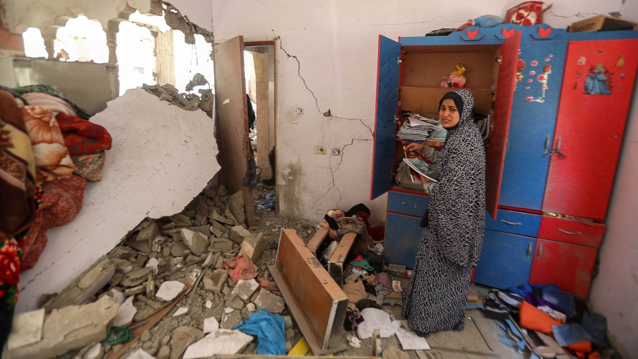 En palestinsk kvinne forsøker å samle sammen tingene sine etter at bygningen leiligheten ligger i ble bombet av israelske luftstyrker natt til fredag.