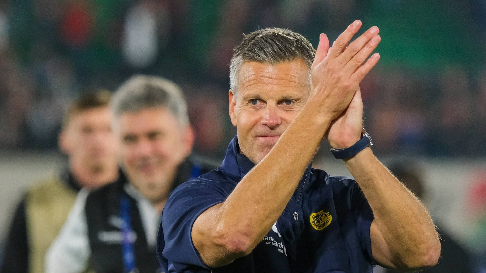 Fotballtrener Kjetil Knutsen klapper til publikum på en arena. (Bildebeskrivelsen er laget av en KI-tjeneste)