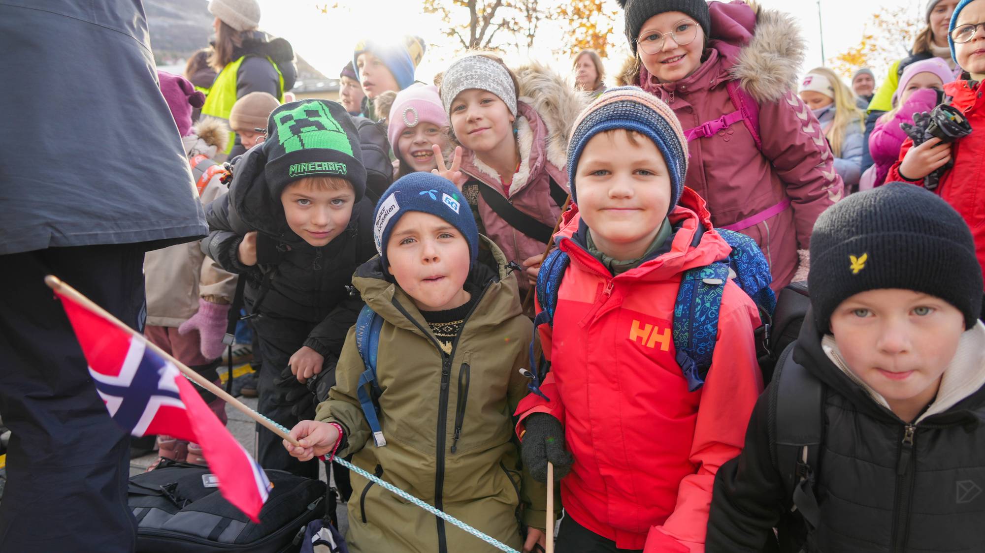 Flere skolebarn med luer og vinterjakker på veiver med flagg