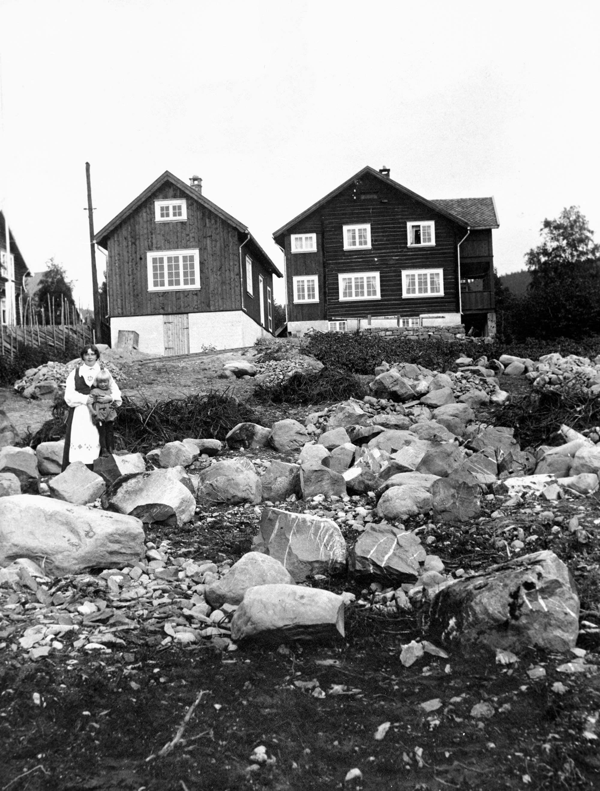 Bilde av Sigrid Undseths hjem med Sigrid Undseth stående foran sammen med et av barna.