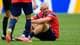 Rebecca Blackwell / AP,NTB Fotballspiller sitter på gresset i rød landslagsdrakt med en annen spiller stående ved siden av. (Bildebeskrivelsen er laget av en KI-tjeneste)