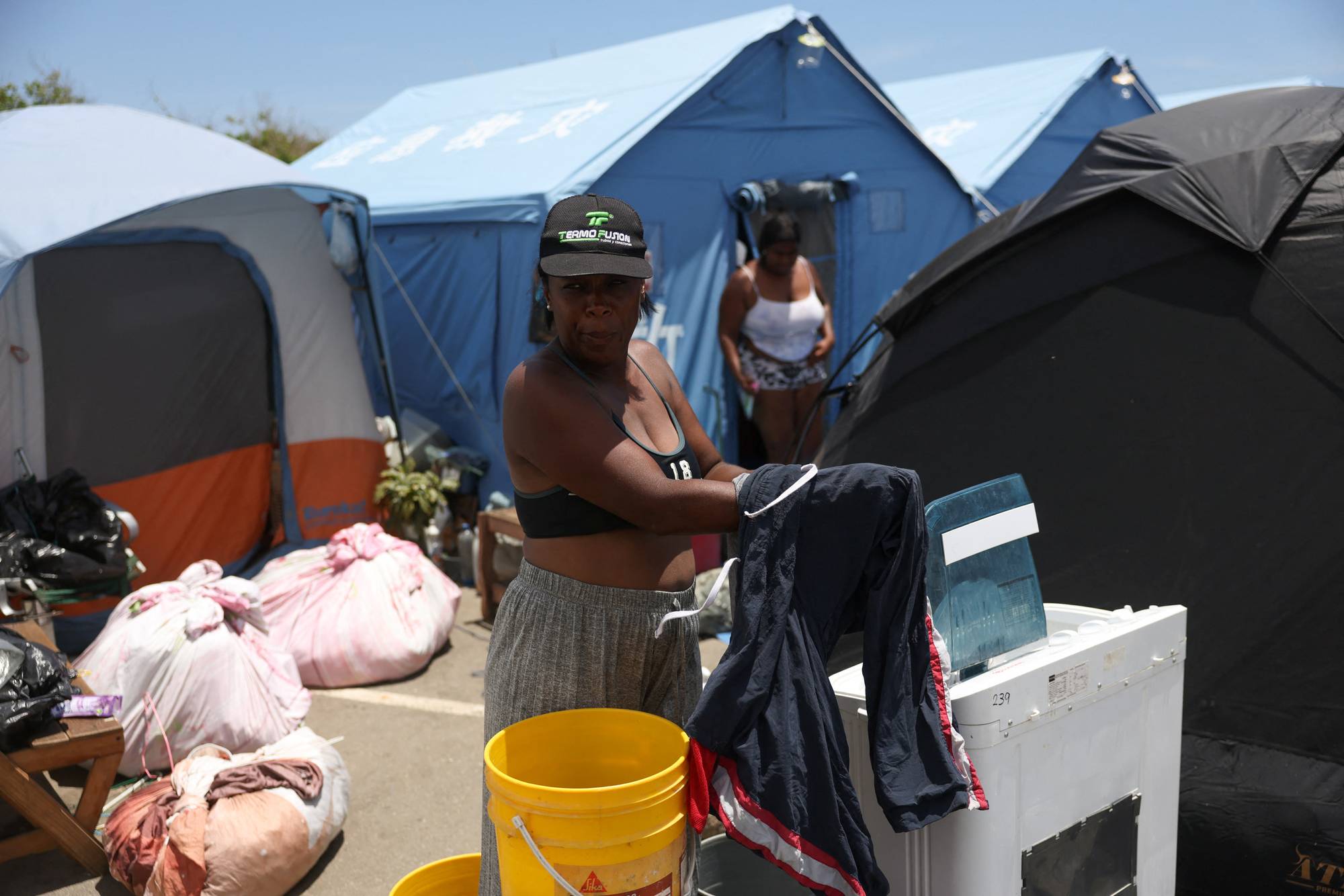 Kvinne vasker klær i baljer i en teltleir i Catia La Mar, La Guaira i Venezuela en måned etter jordskjelvene 