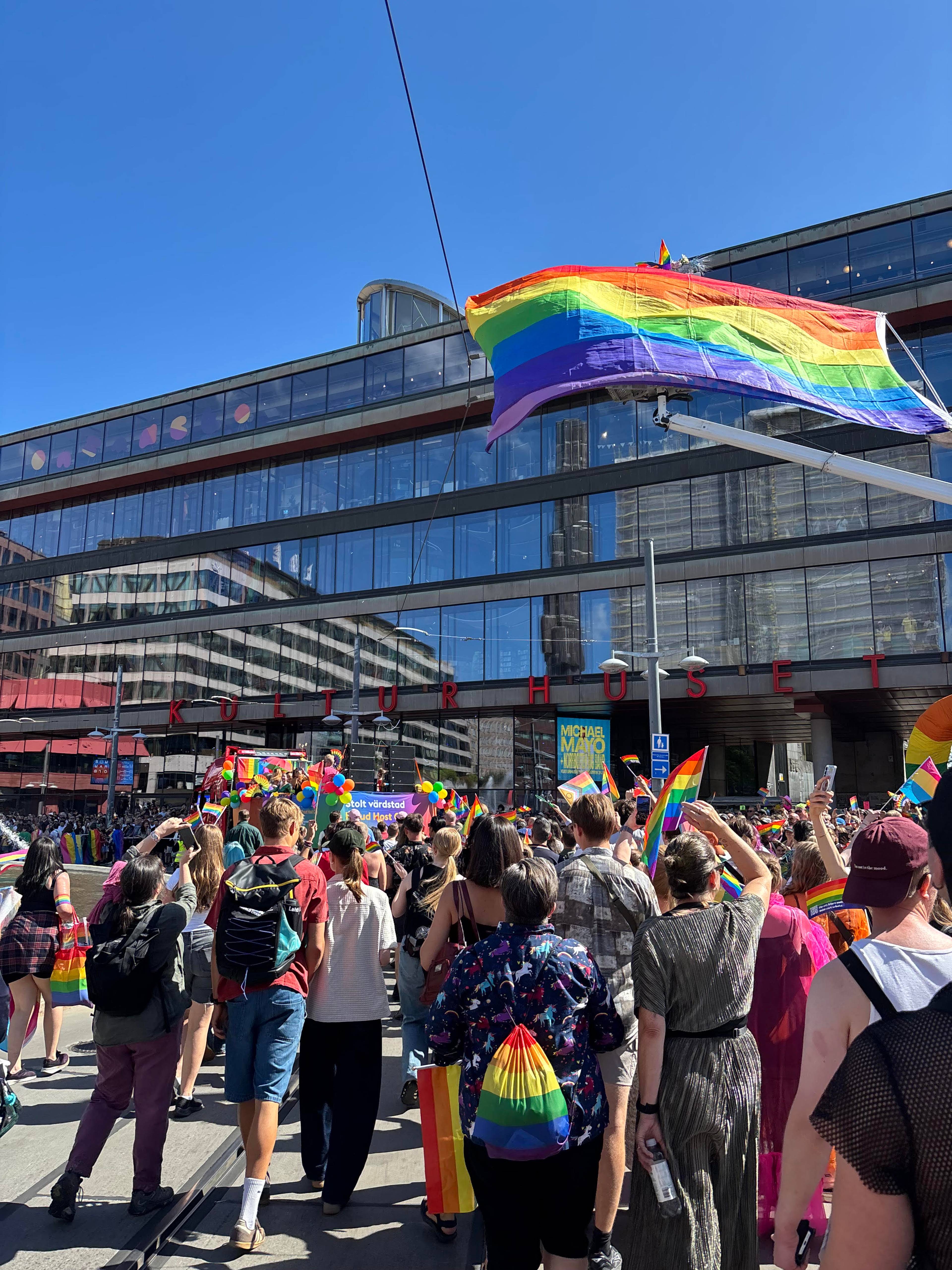 Boilde av en forslaming av mennesker, et prideflag flagrer i vinden