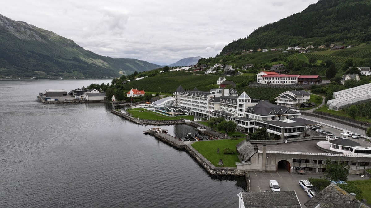 Hotel Ullensvang ved Sørfjorden i Hardanger, omgitt av fjell og bebyggelse. (Bildebeskrivelsen er laget av en KI-tjeneste) FOTO: Odd Arne Olderbakk/NRK