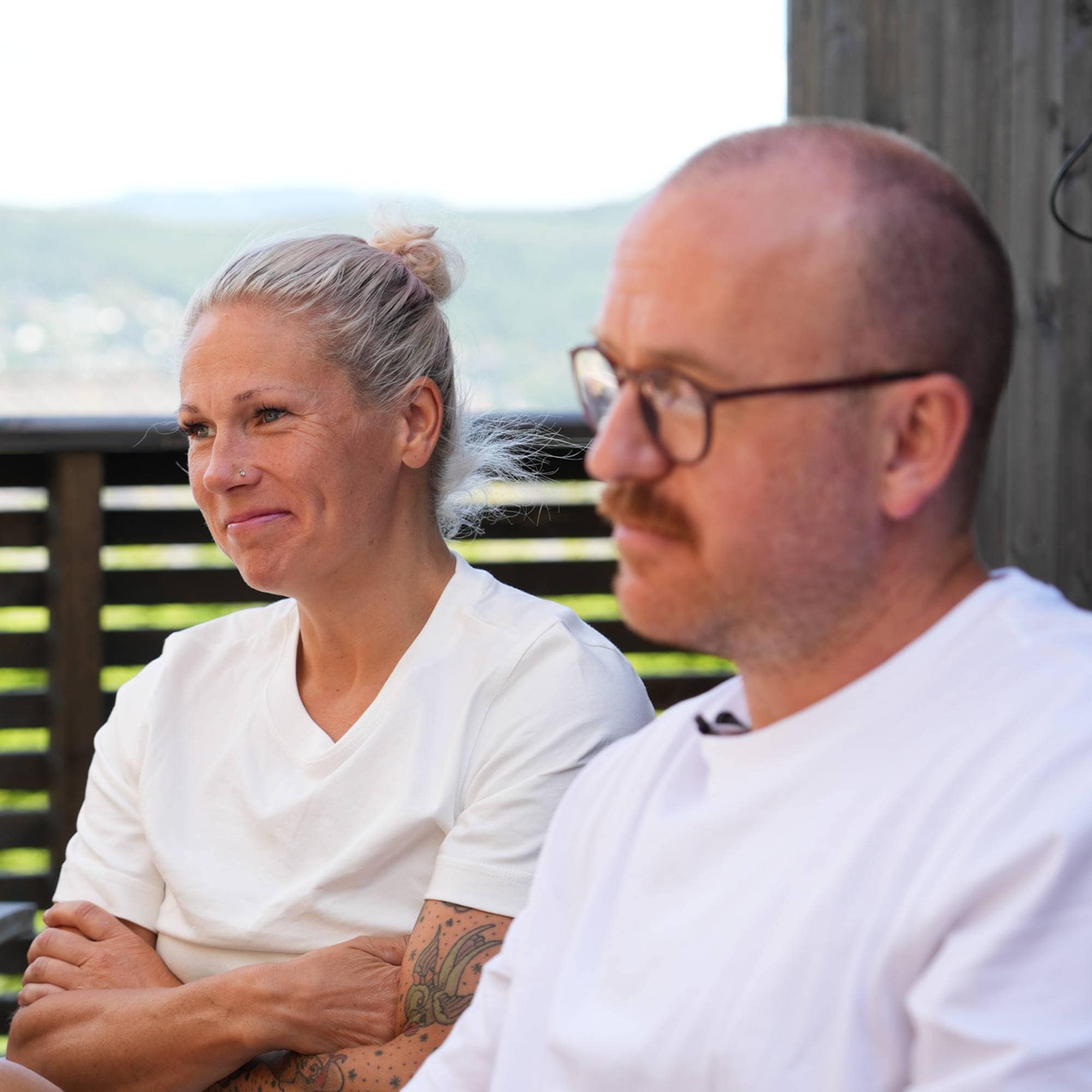 Tre personer som sitter ute og ser mot en annen som snakker. 