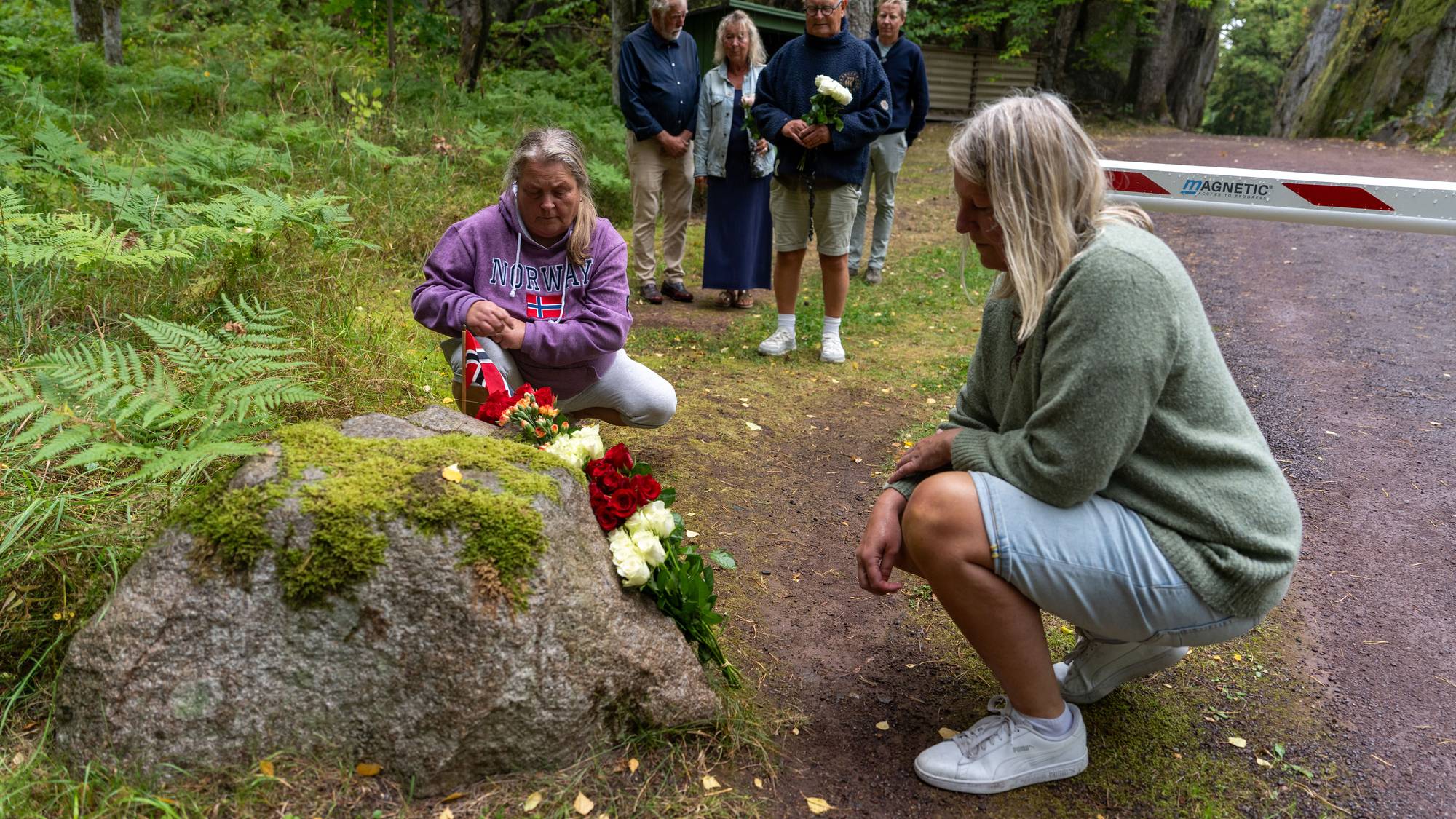 En gruppe mennesker legger ned blomster ved innkjørselen til hytta til kongefamilien på Mågerø