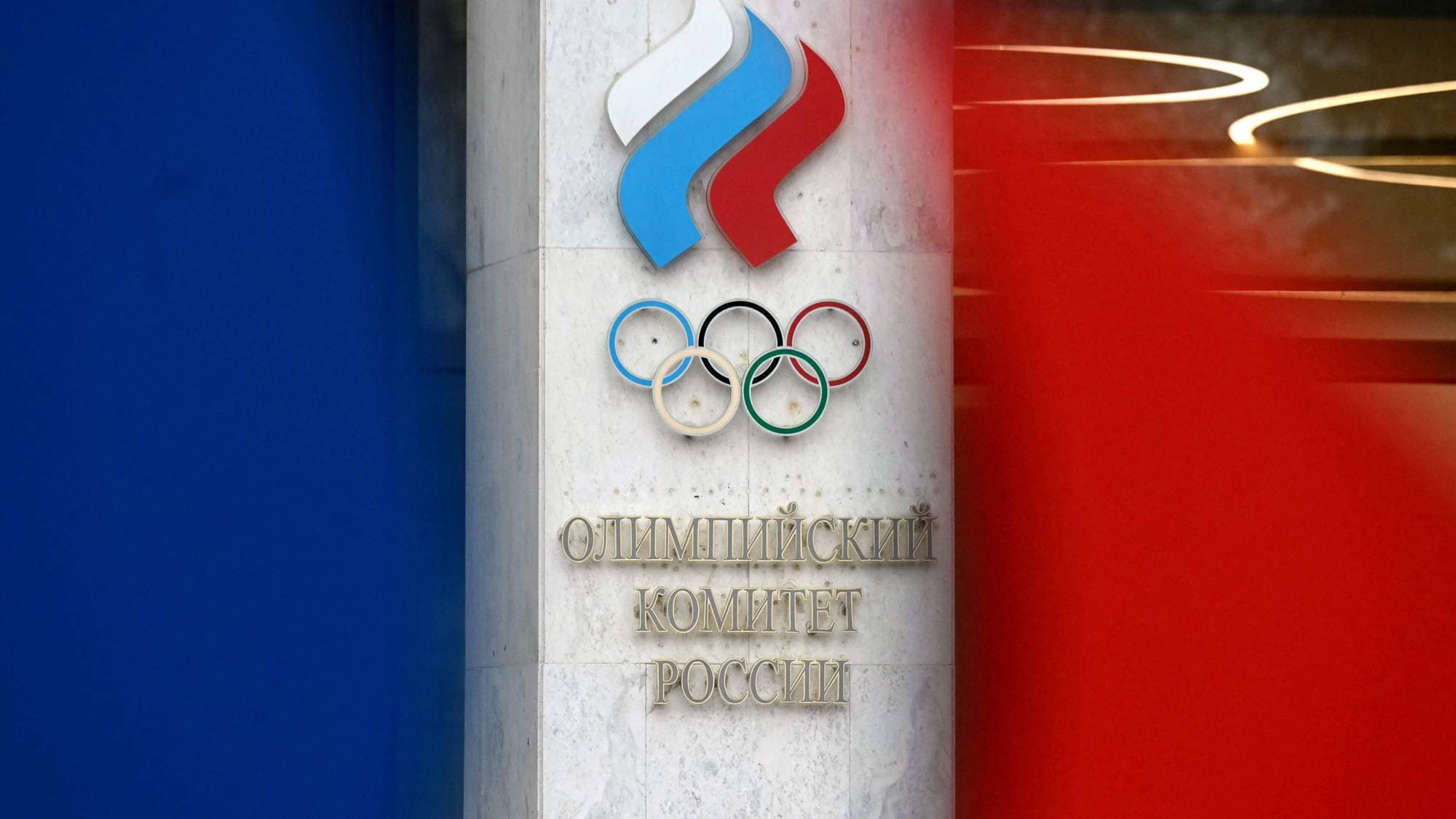 Logo for Den olympiske komité i Russland montert på en vegg med russiske flaggfarger. (Bildebeskrivelsen er laget av en KI-tjeneste)