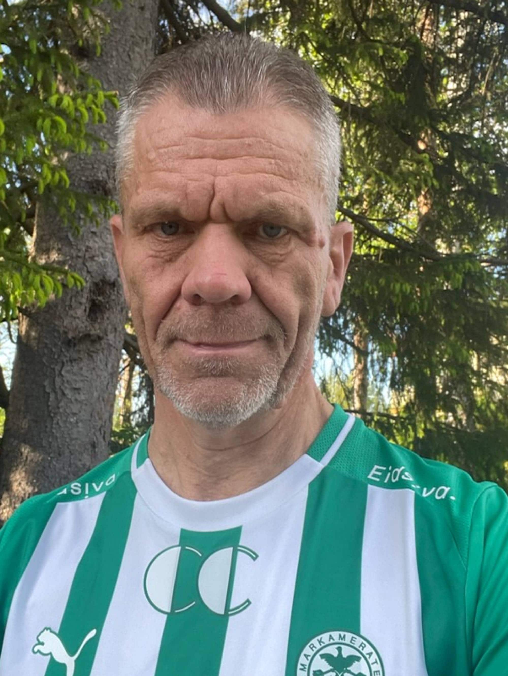Mann i grønn og hvit t-skjorte seg i kamera
