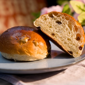 Et bolle med rosiner er delt i to og ligger på en tallerken.