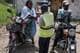 BADRU KATUMBA / AFP,NTB En helsearbeider vasker hendene til motorsyklister med håndsprit ved en grenseovergang
