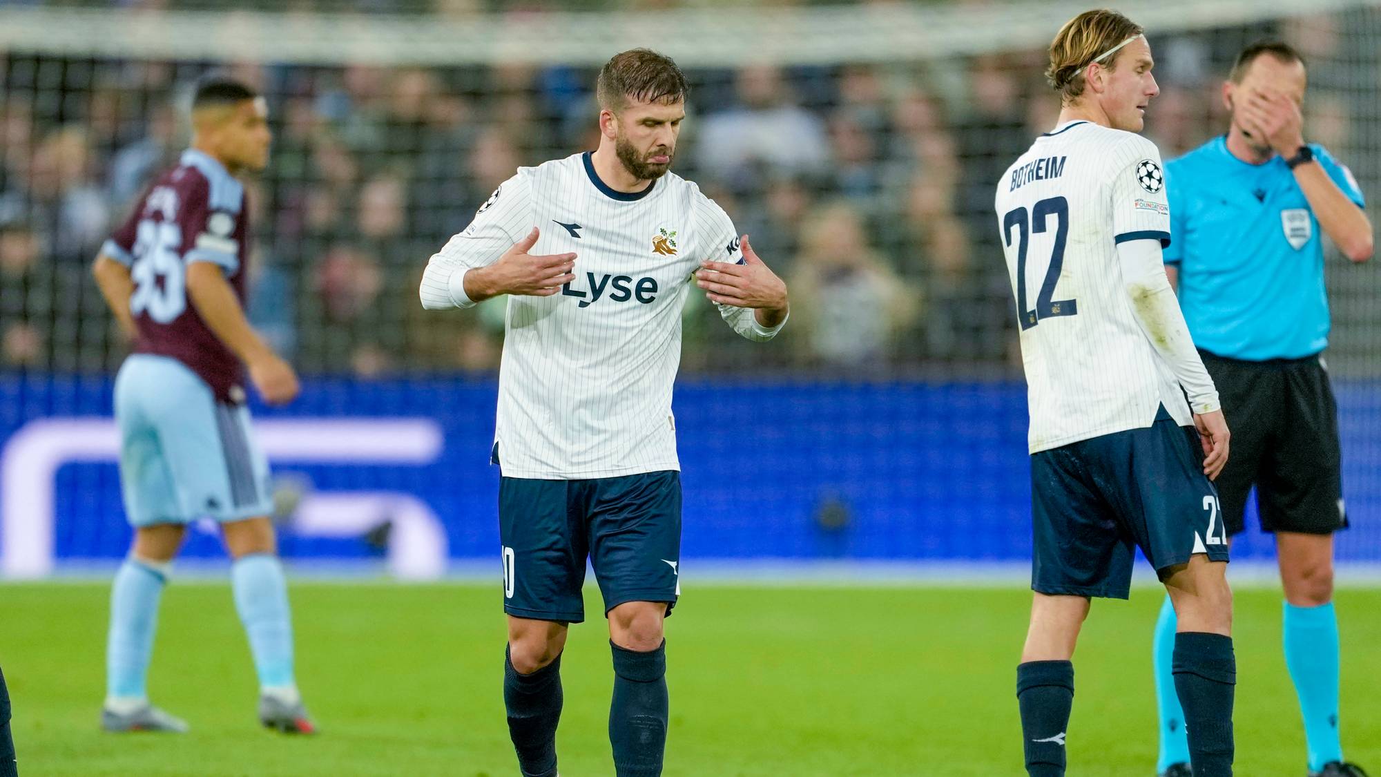 Skuffede Viking-spillere på banen etter en fotballkamp. Dommeren står i bakgrunnen. (Bildebeskrivelsen er laget av en KI-tjeneste)