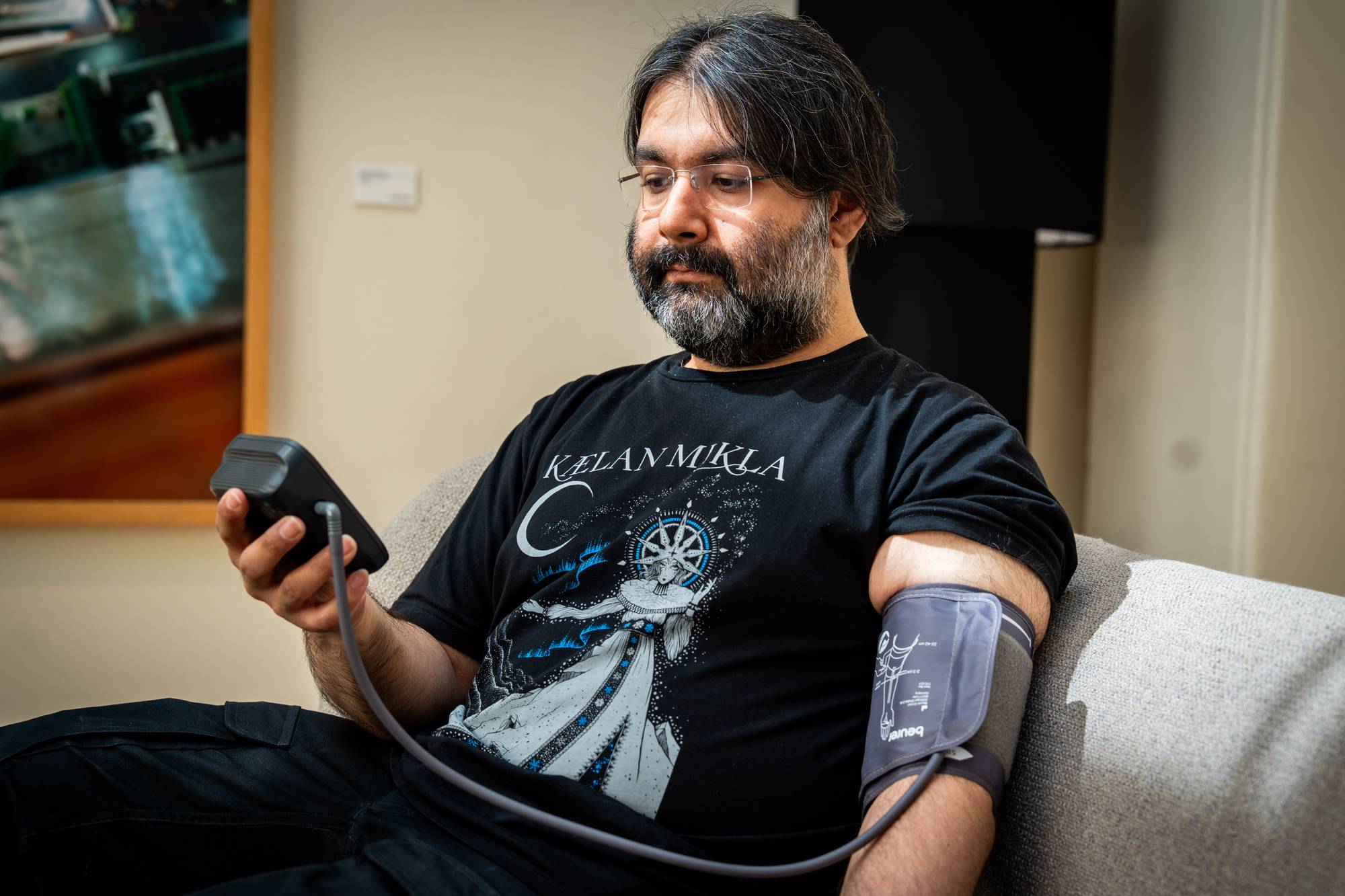 Mann sitter i stol og måler blodtrykket