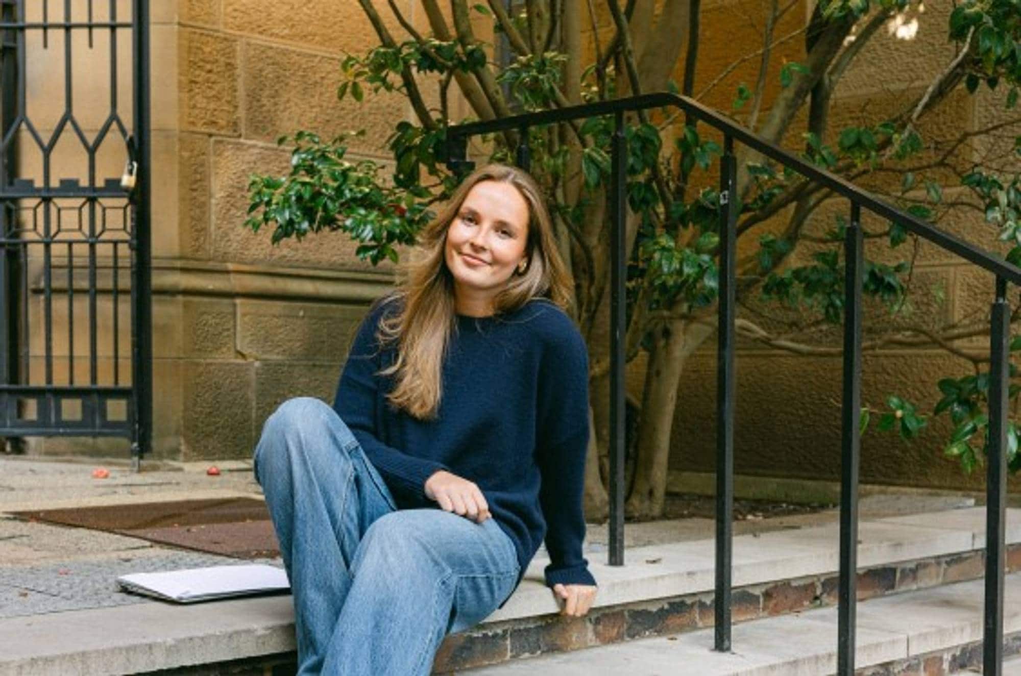Prinsesse Ingrid Alexandra sitter på noen trapper iført blå jeans og en mørkeblå genser. 