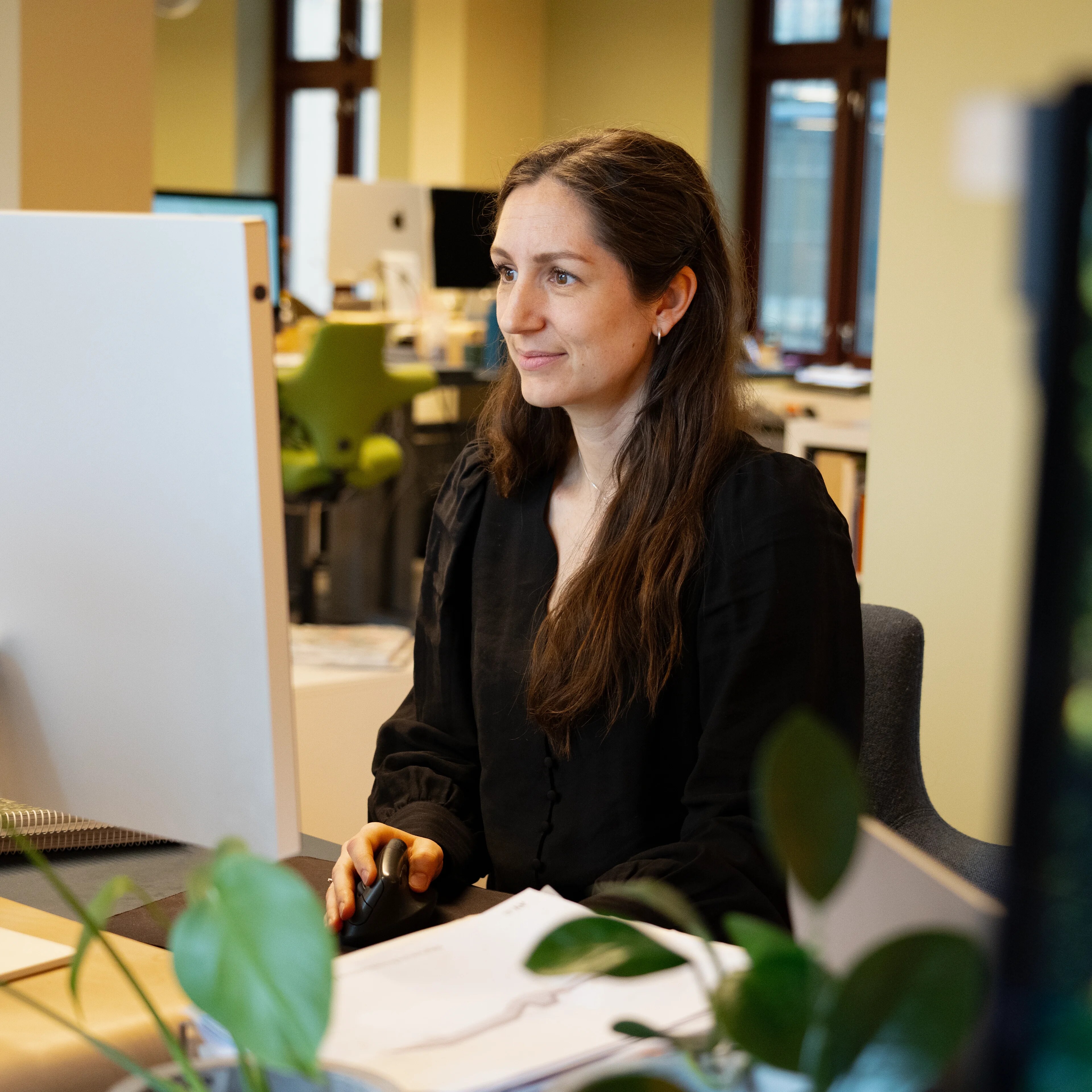 Kvinne sitter på et kontor og ser på skjerm