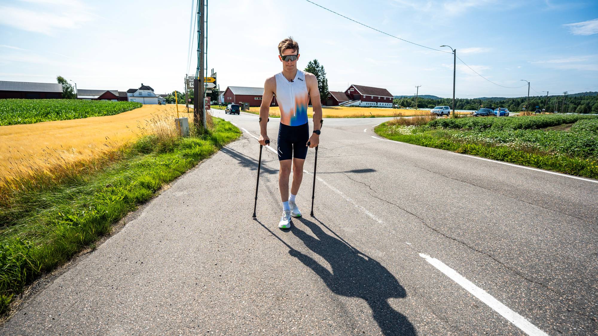 En mann med krykker og treningsdrakt som går på veien.